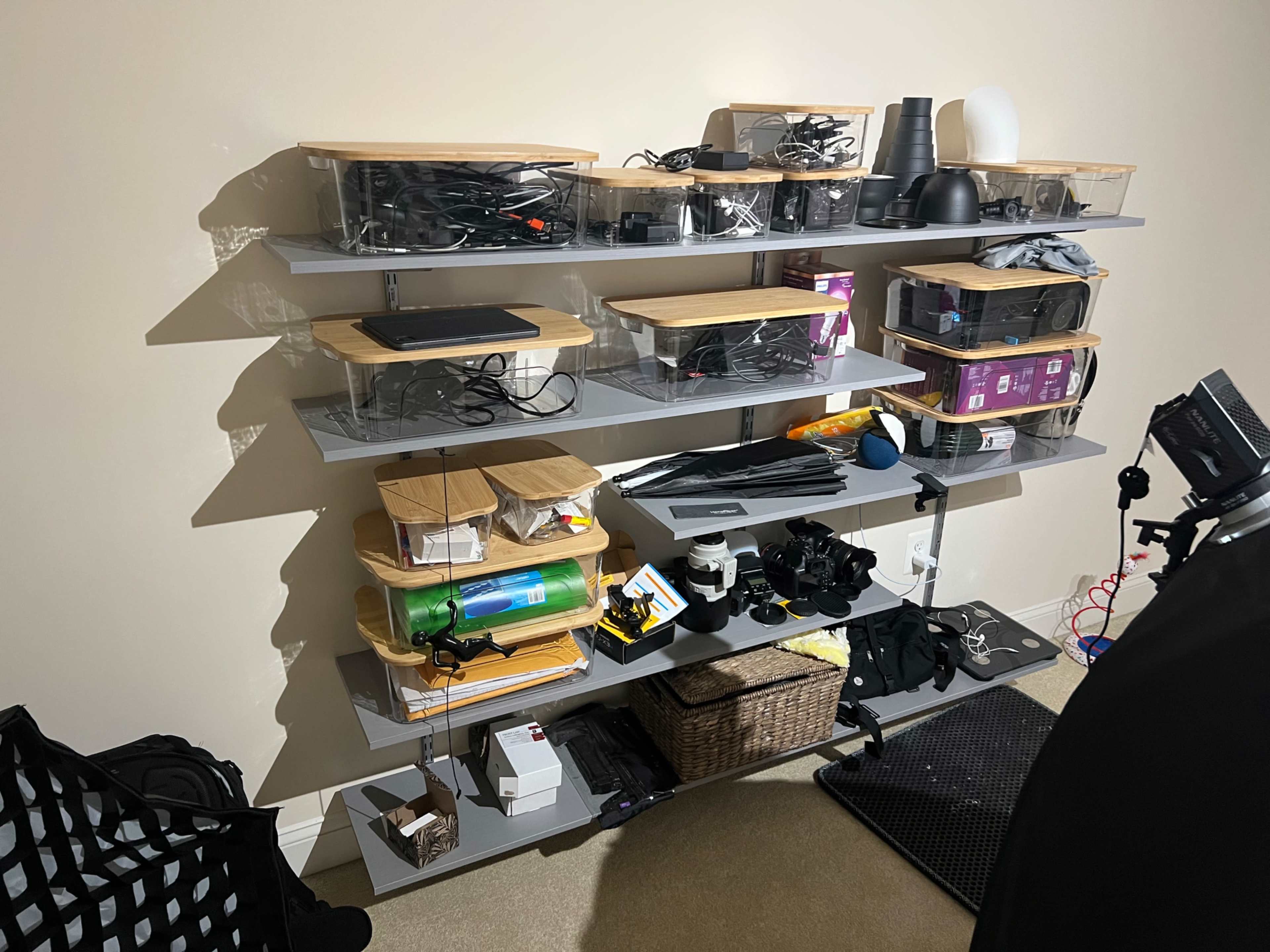 A cluttered shelf with multiple storage containers filled with various items, including cables, equipment, and accessories.