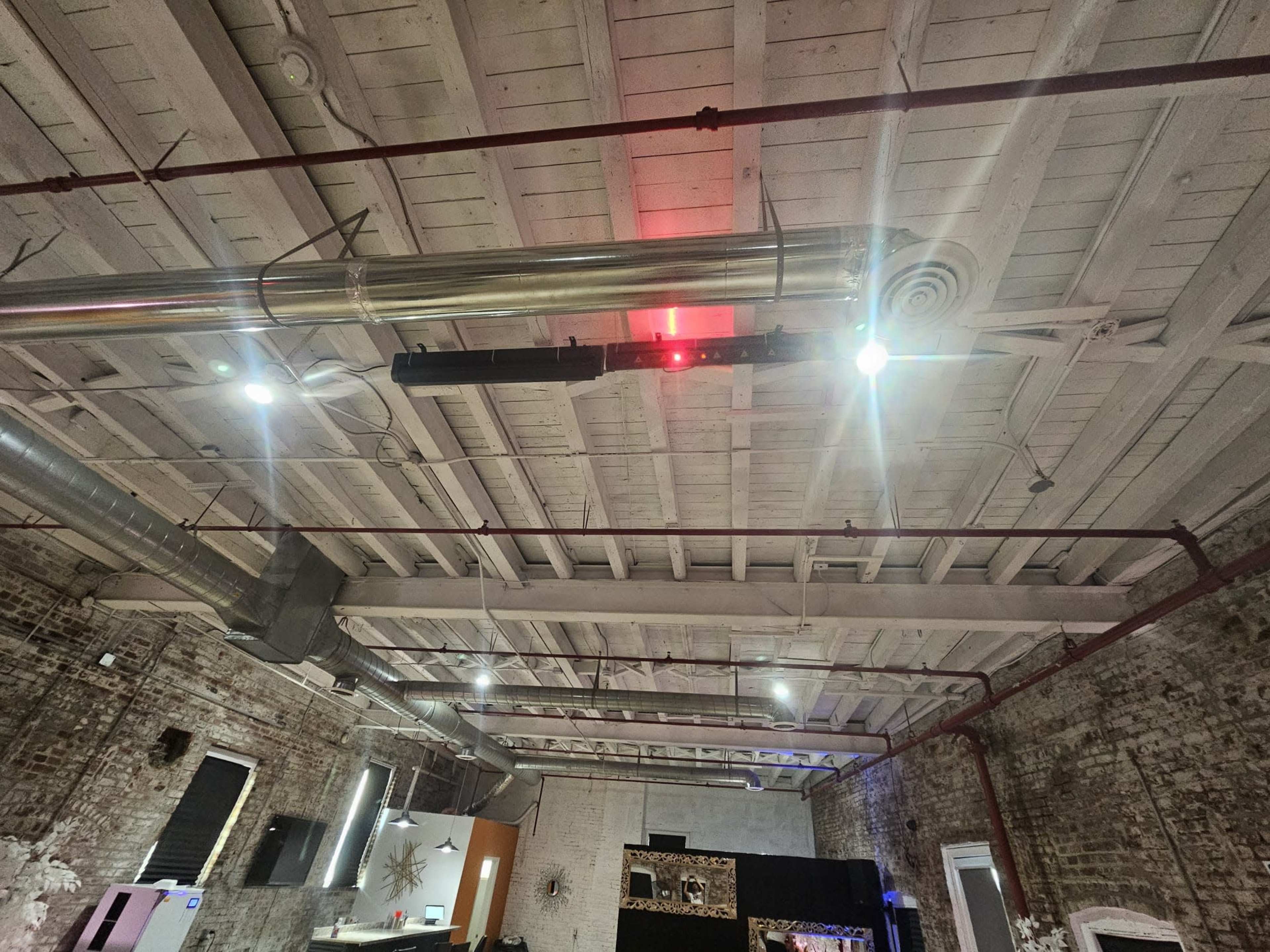 A high ceiling with exposed wooden beams and industrial lighting in a spacious interior.
