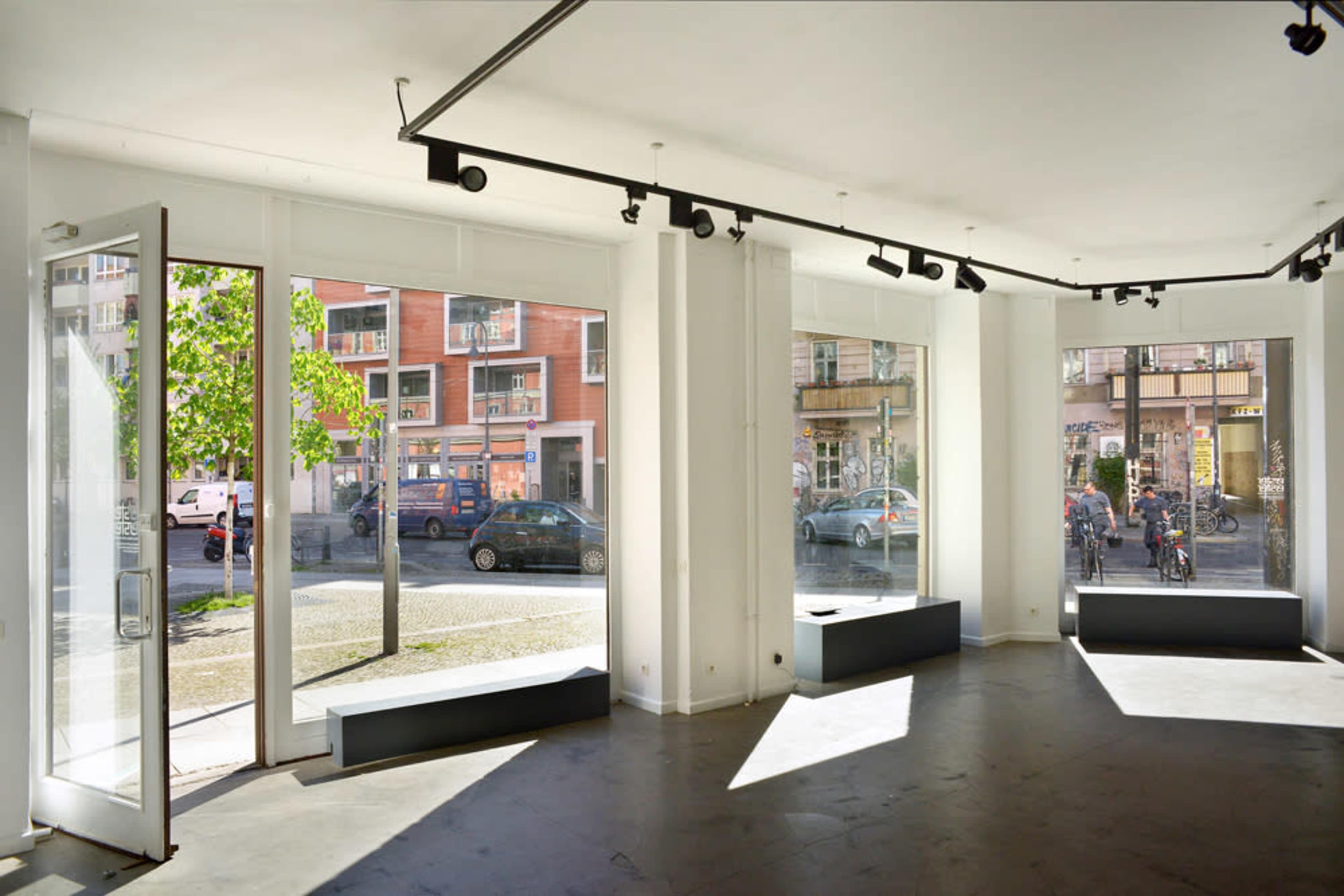 A bright, open room with large windows and a minimalist design, featuring an unobstructed view of a street outside.