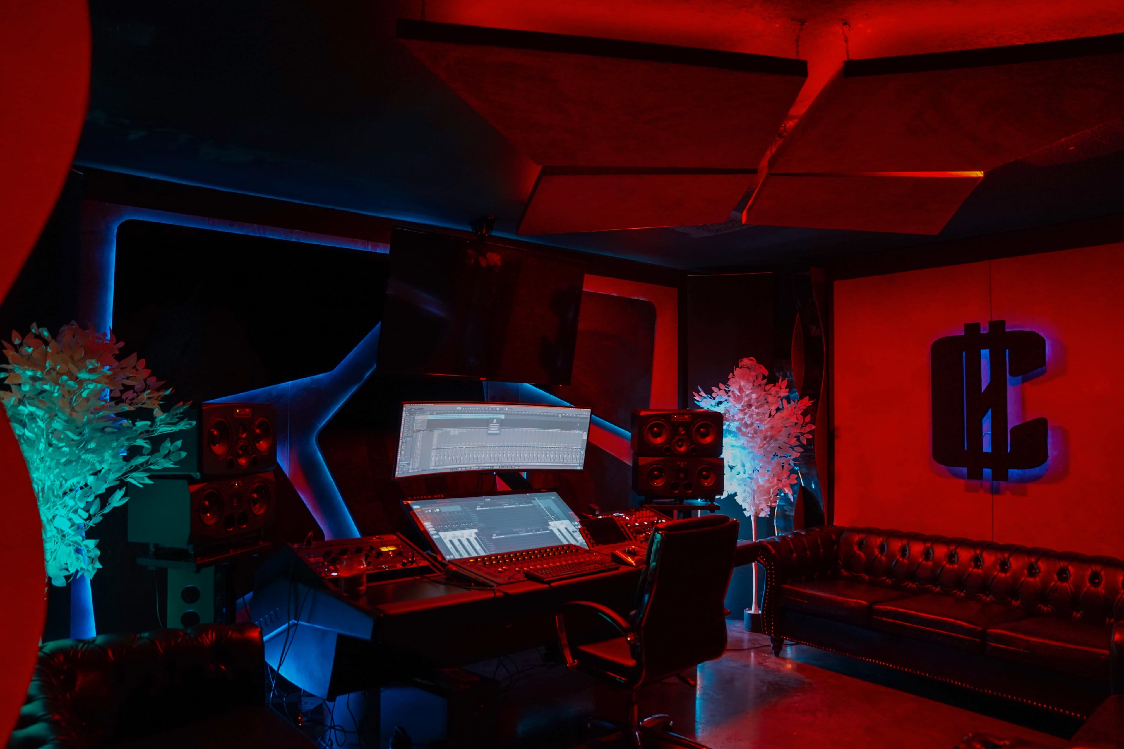 A music production studio featuring a large mixing desk, multiple speakers, and neon lighting accents.