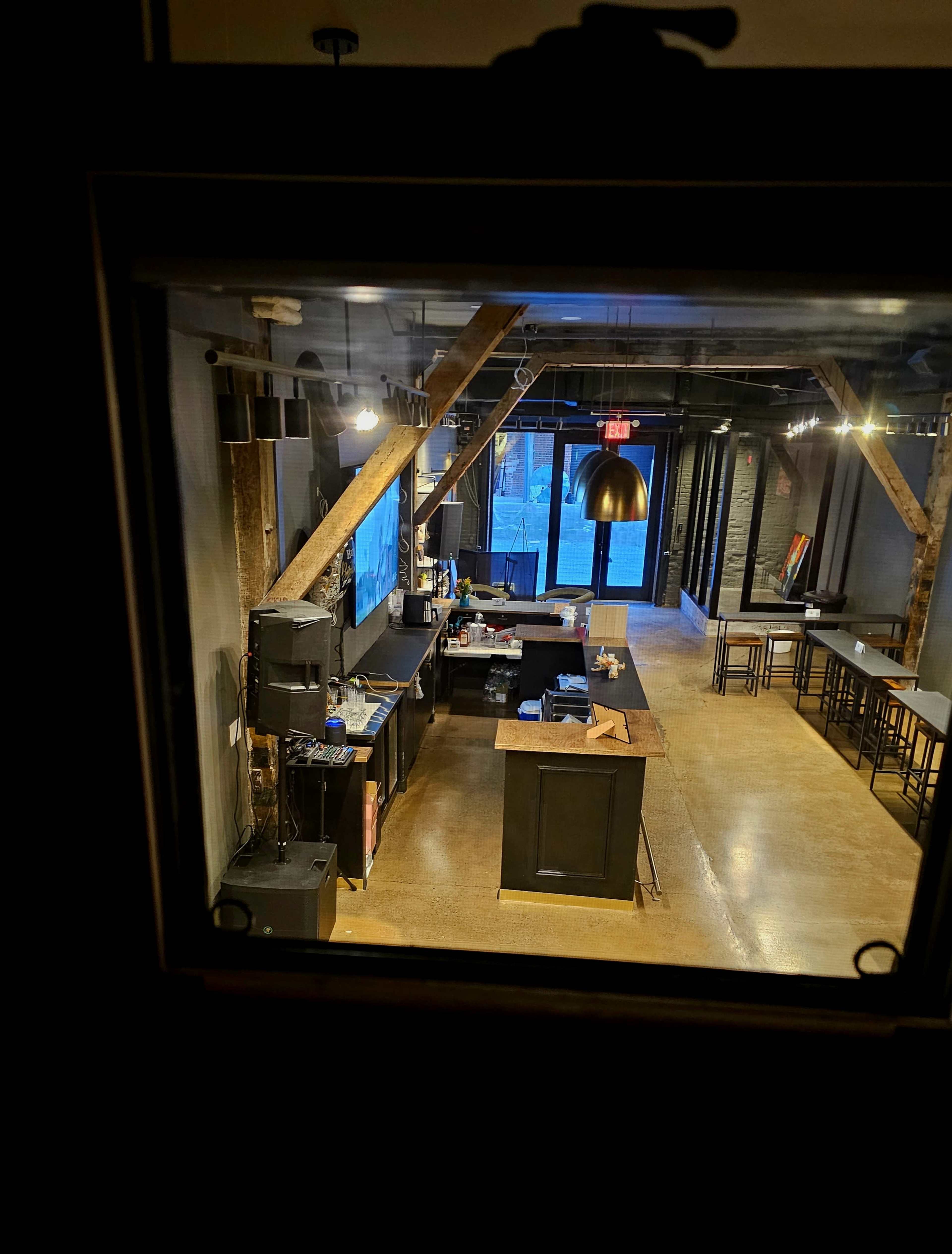 The image shows the interior of a restaurant with wooden beams, a bar area, and seating arrangements, illuminated by overhead lights.