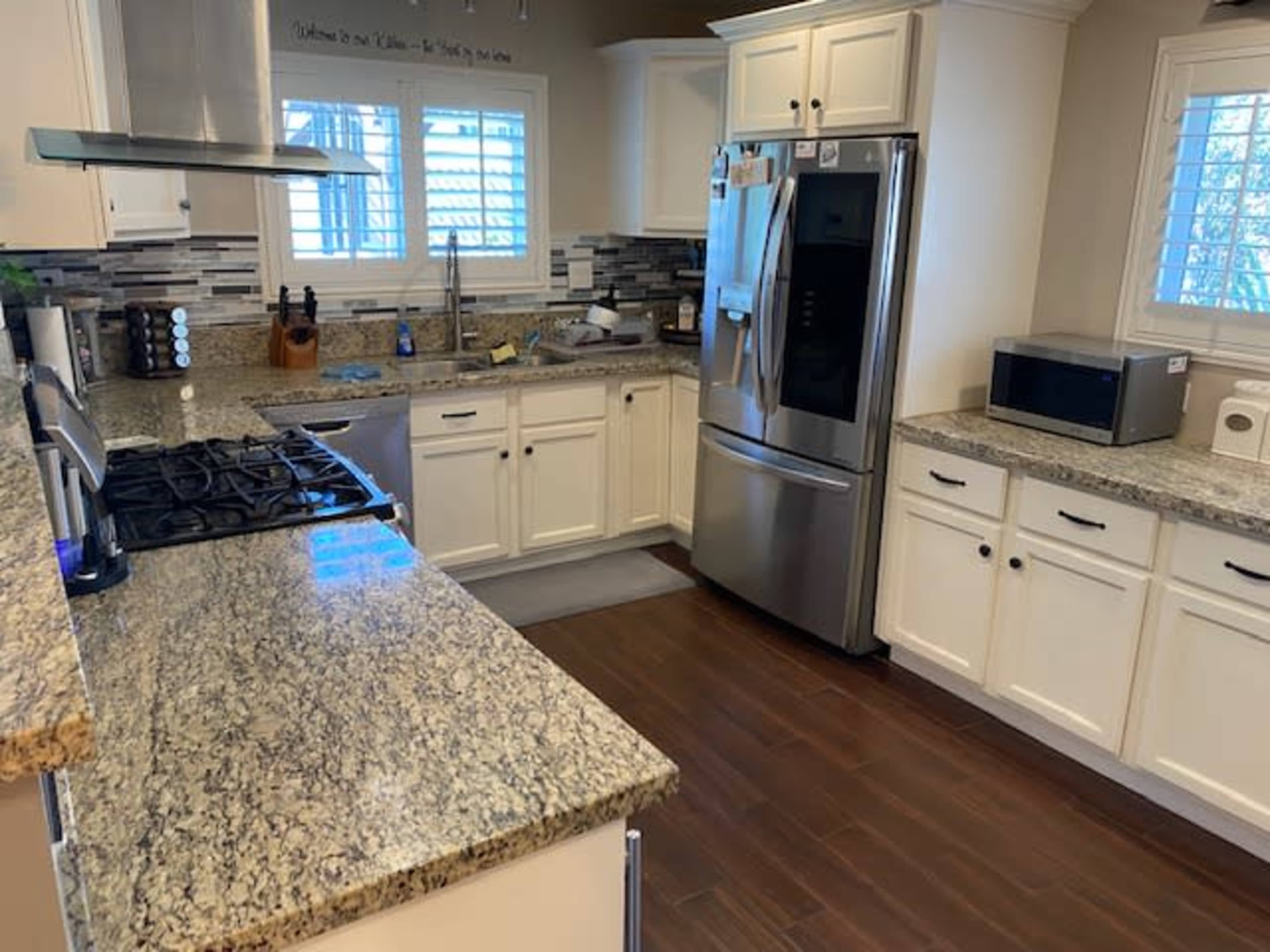 A modern kitchen features granite countertops, stainless steel appliances, and white cabinetry.