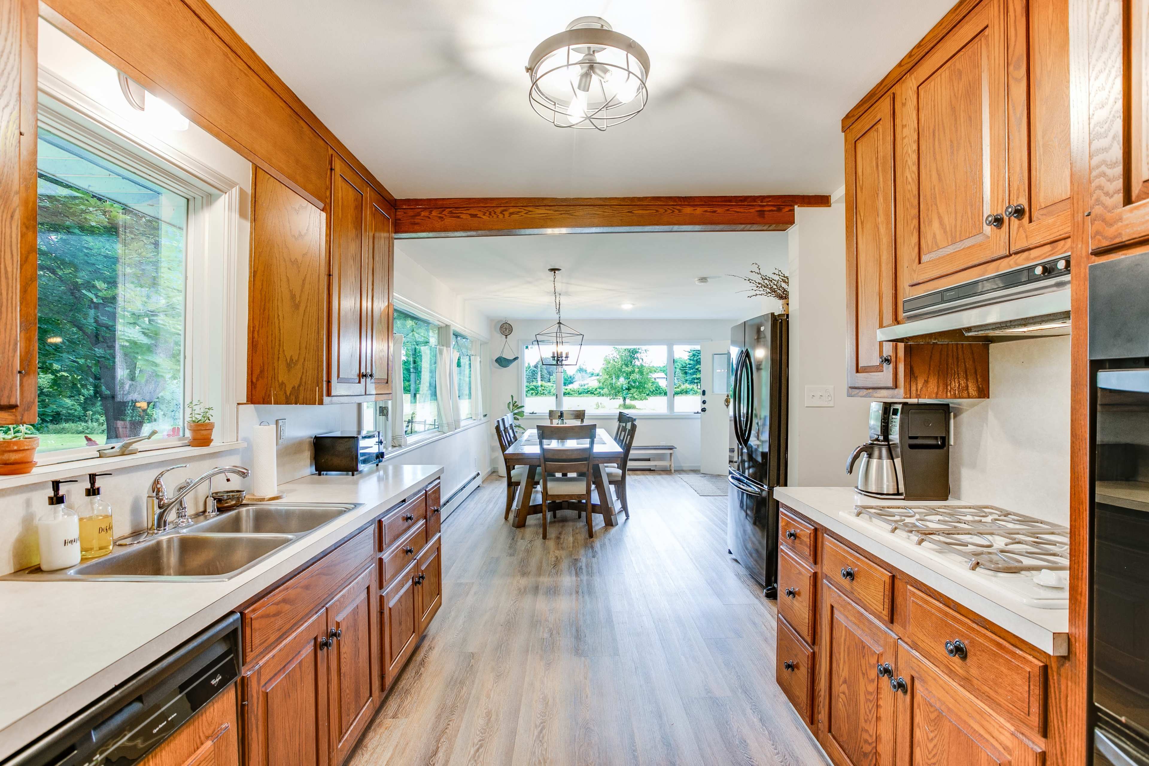 A modern kitchen with wooden cabinetry and a view of a dining area through an open passage.