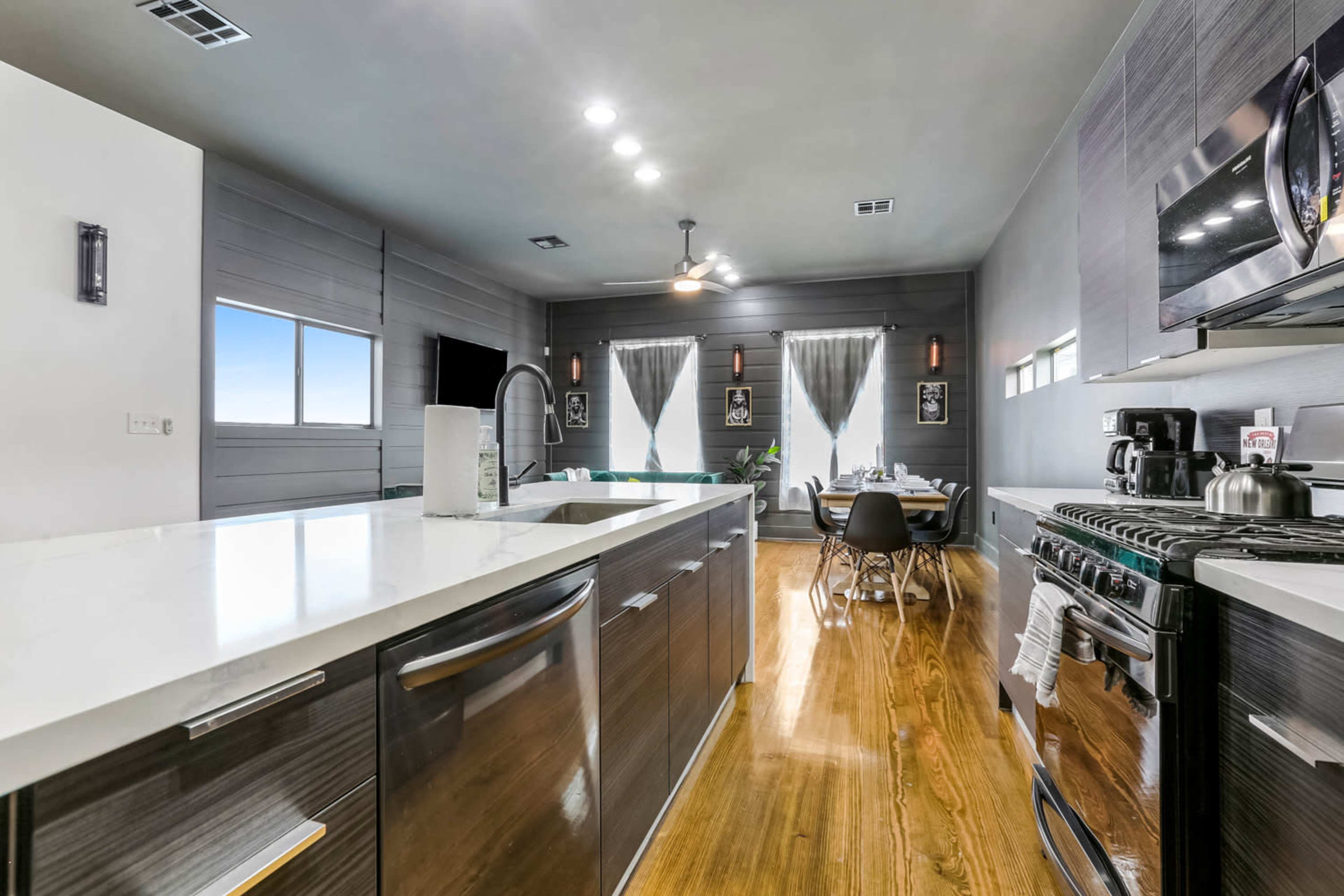 A modern kitchen features stainless steel appliances, a large island with a white countertop, and an adjoining dining area.