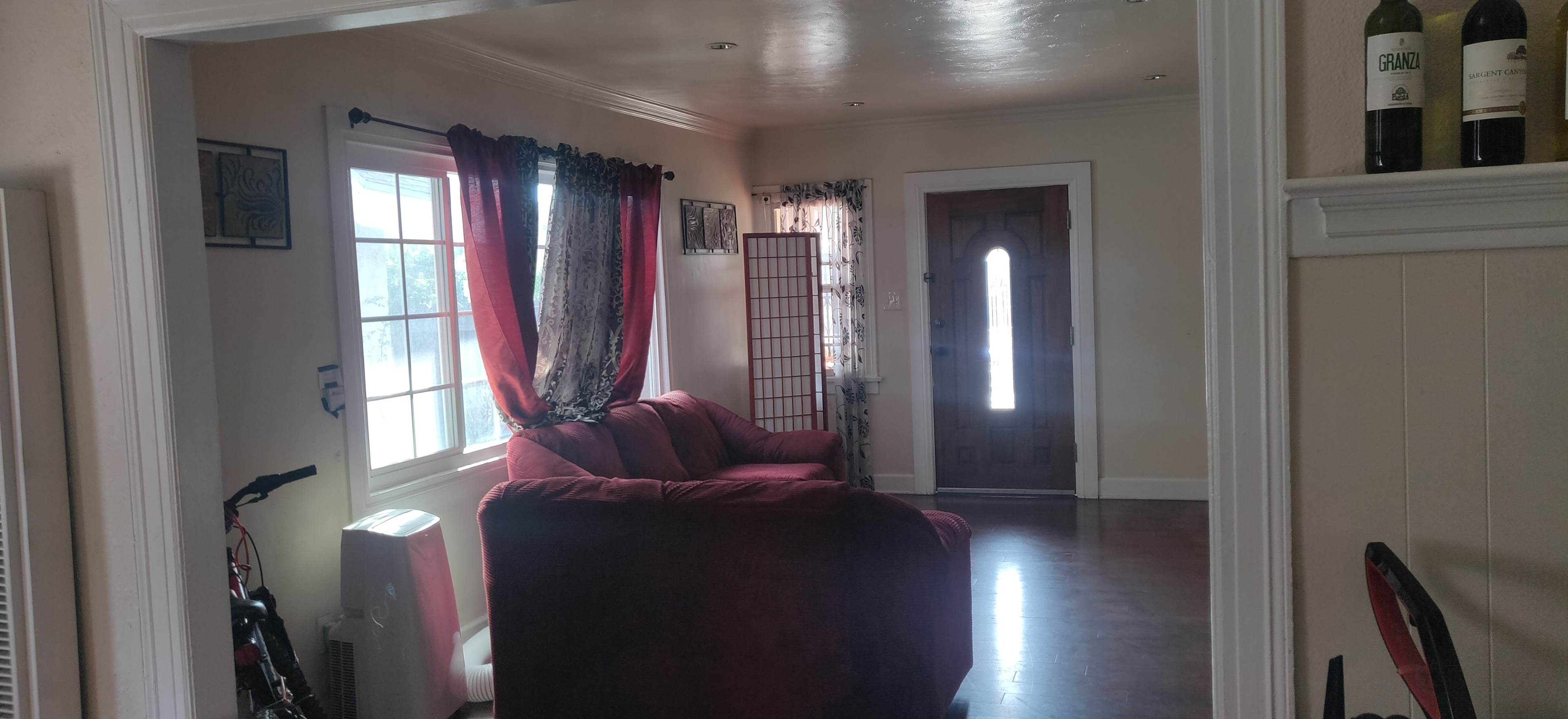 The image shows a living room with a red couch, a window with curtains, and a door leading outside.