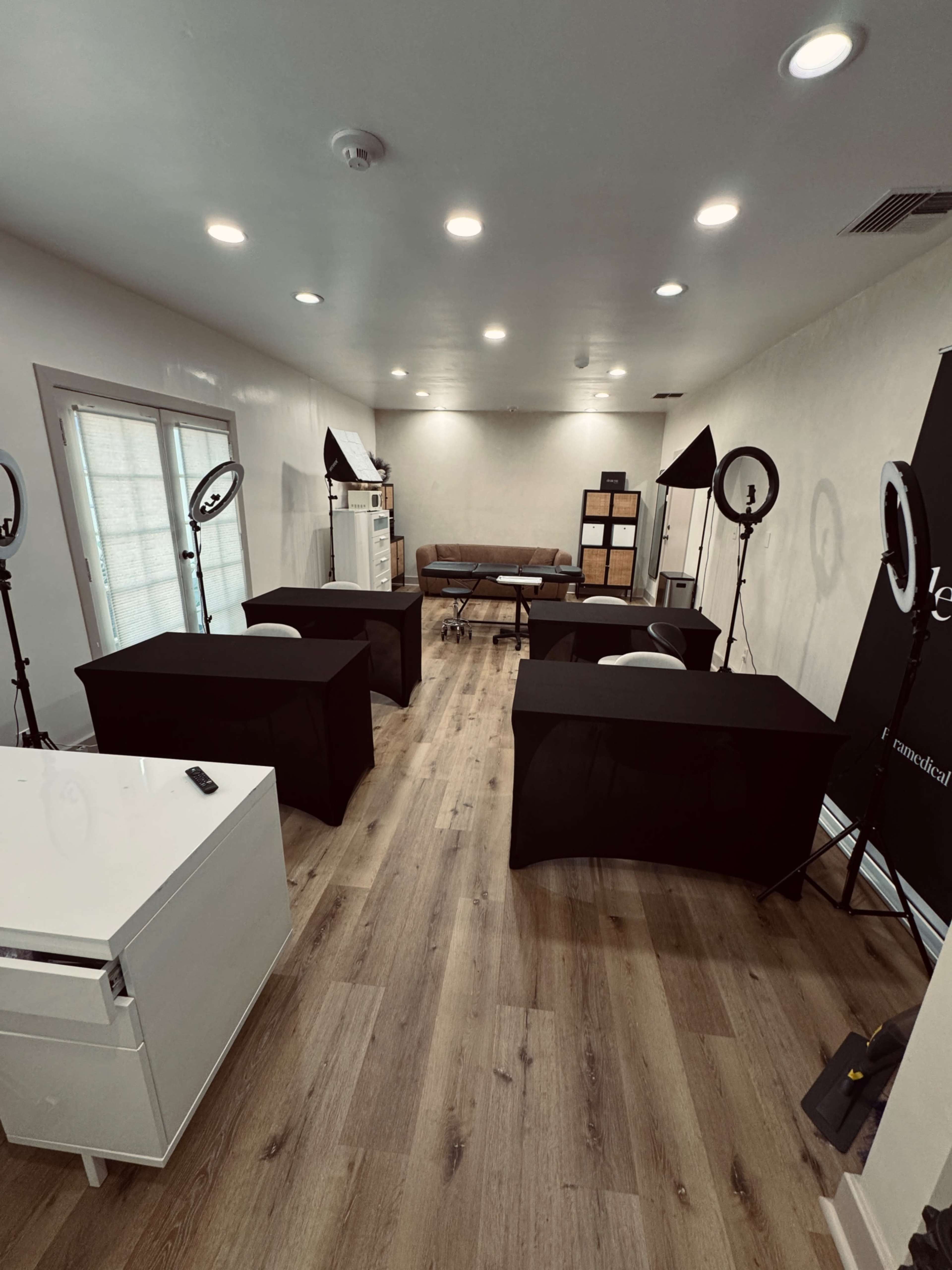 The image shows a well-lit room with four tables arranged in a professional setup, surrounded by lighting equipment and a couch in the background.