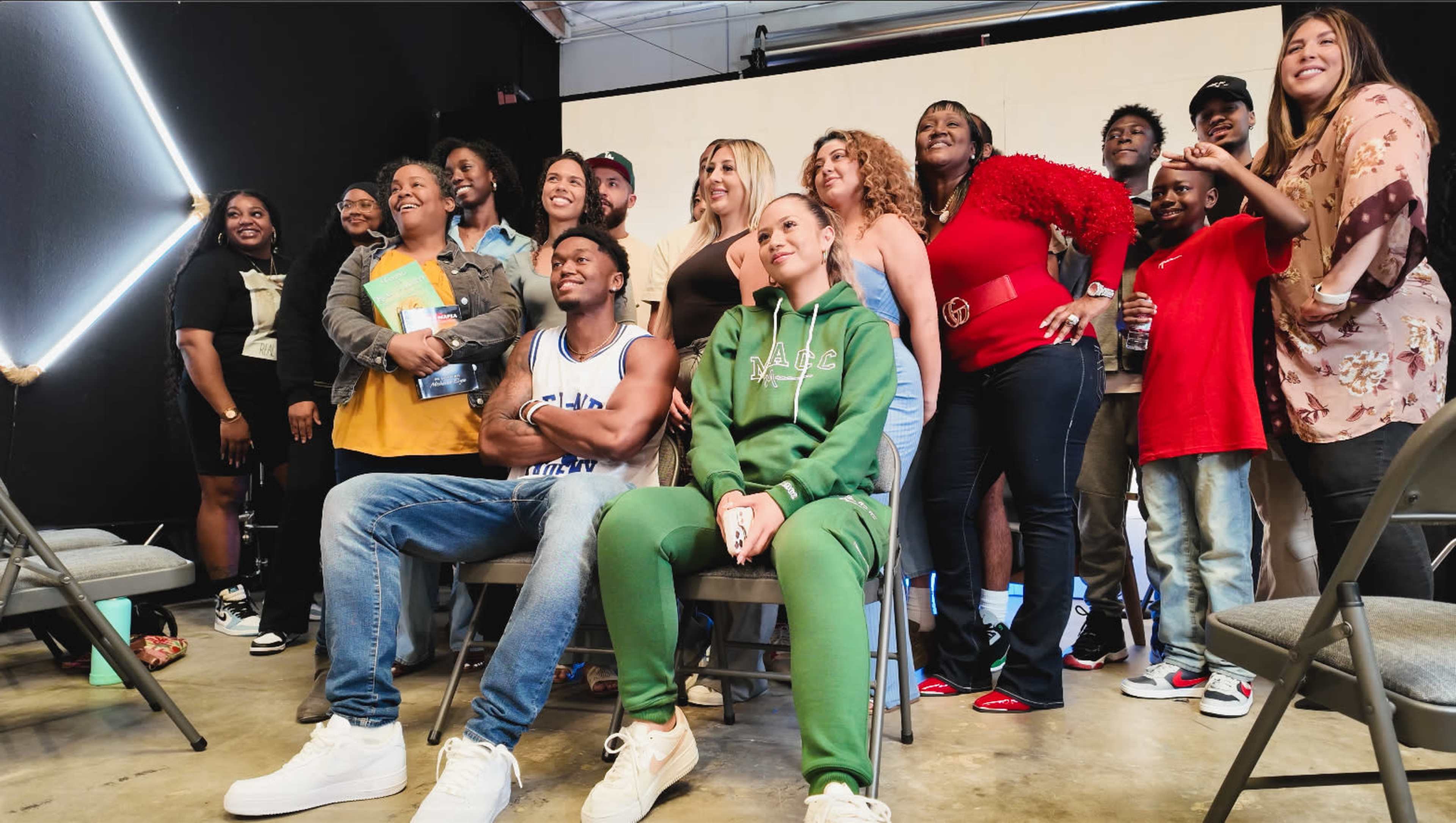 A diverse group of people, including men, women, and children, poses together for a photo in a brightly lit room.