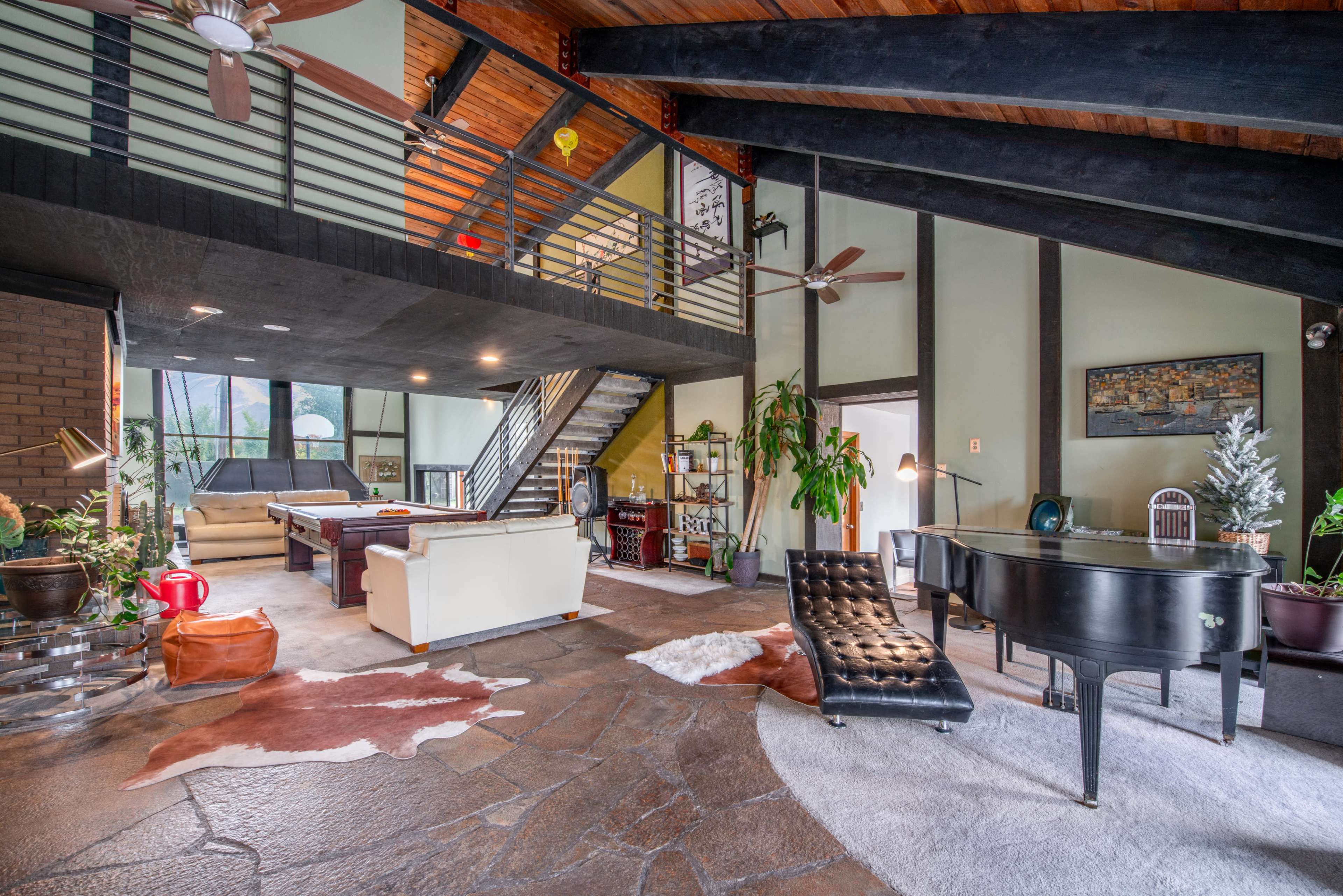 A spacious modern living room with a double-height ceiling, featuring a piano, contemporary furniture, and large windows that provide natural light.