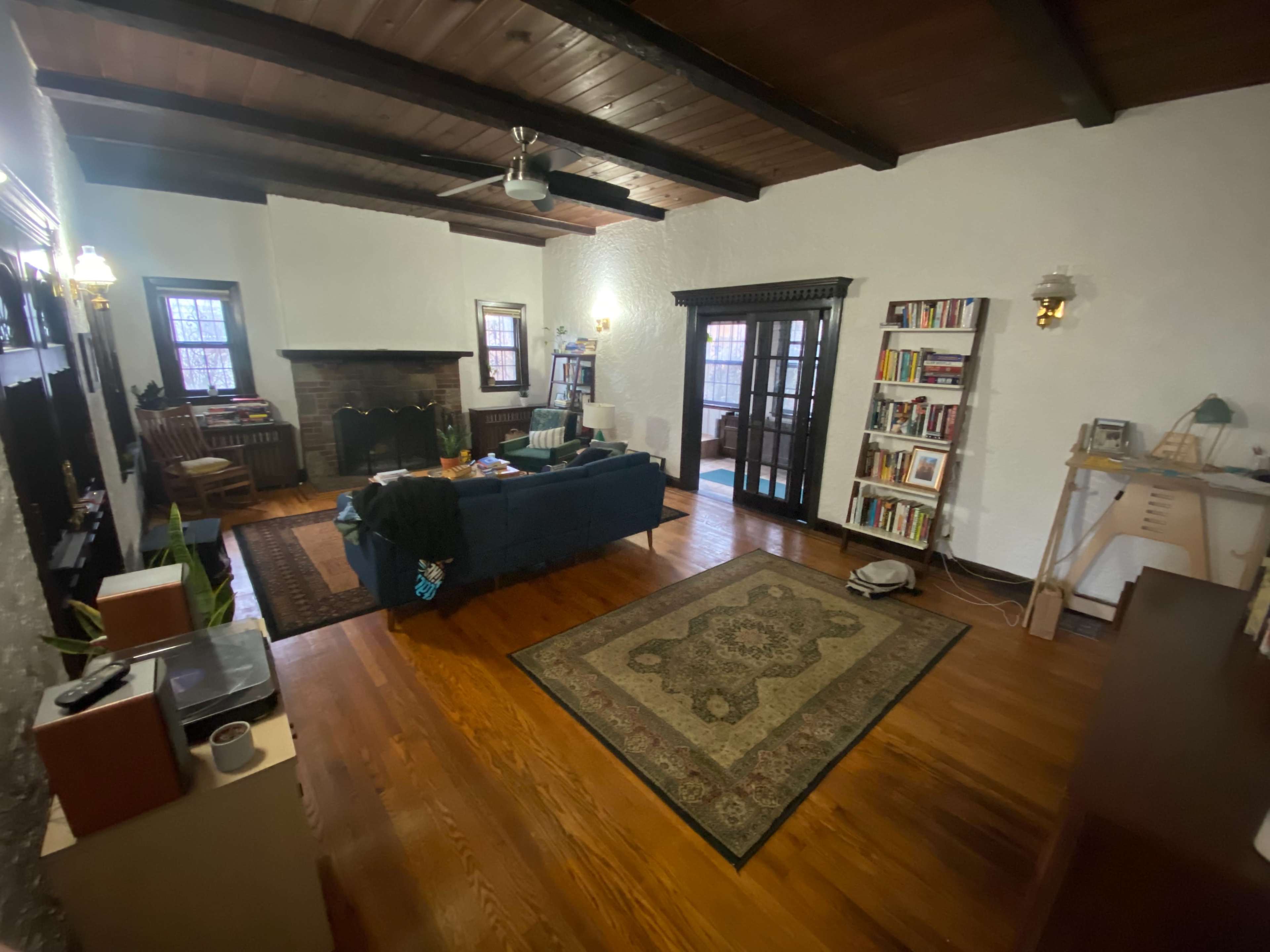 A spacious living room with a fireplace, bookshelves, a blue couch, and large windows.