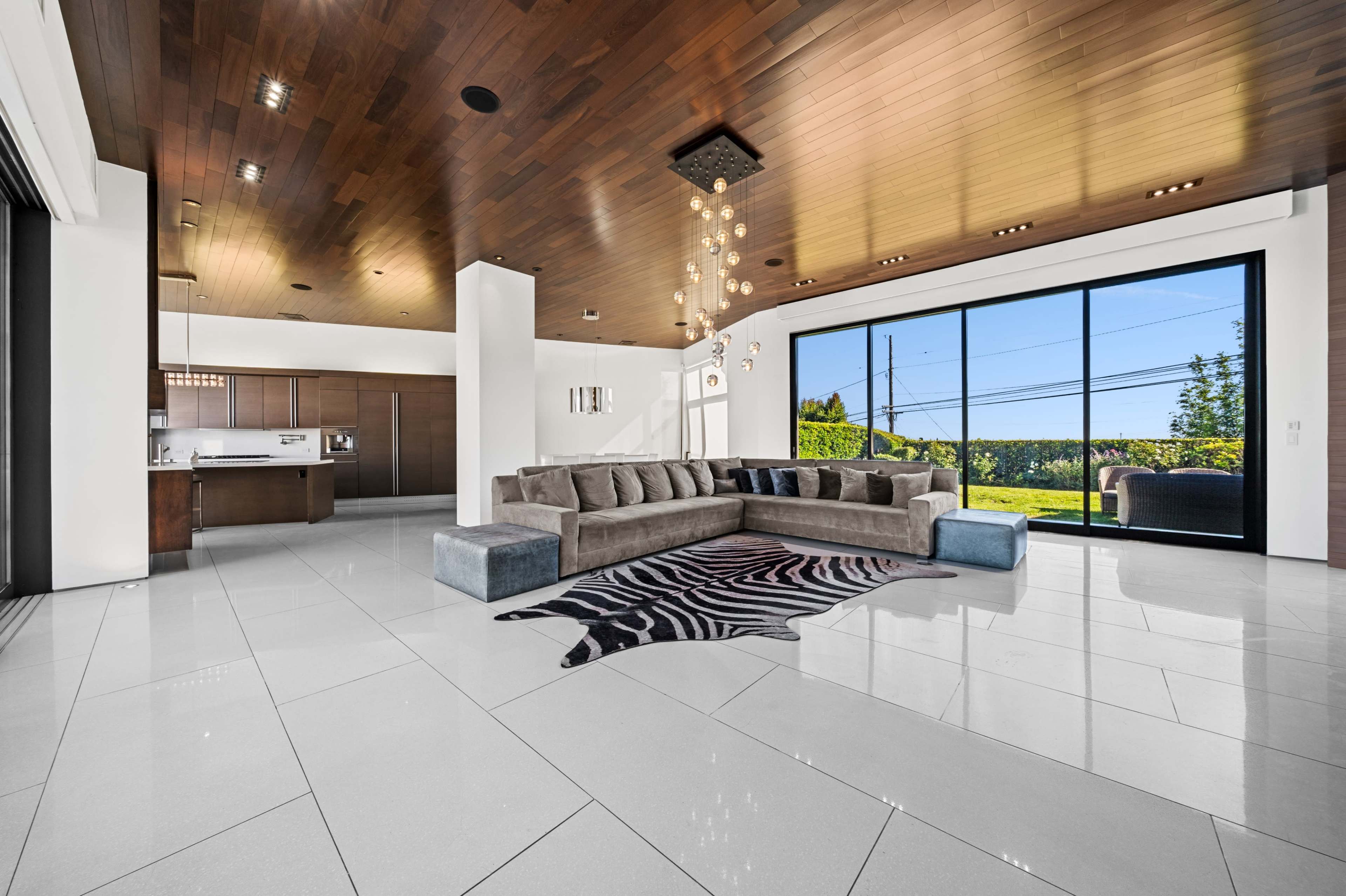 A spacious living room featuring a large sectional sofa, a patterned rug, and large windows providing a view of the outdoors.
