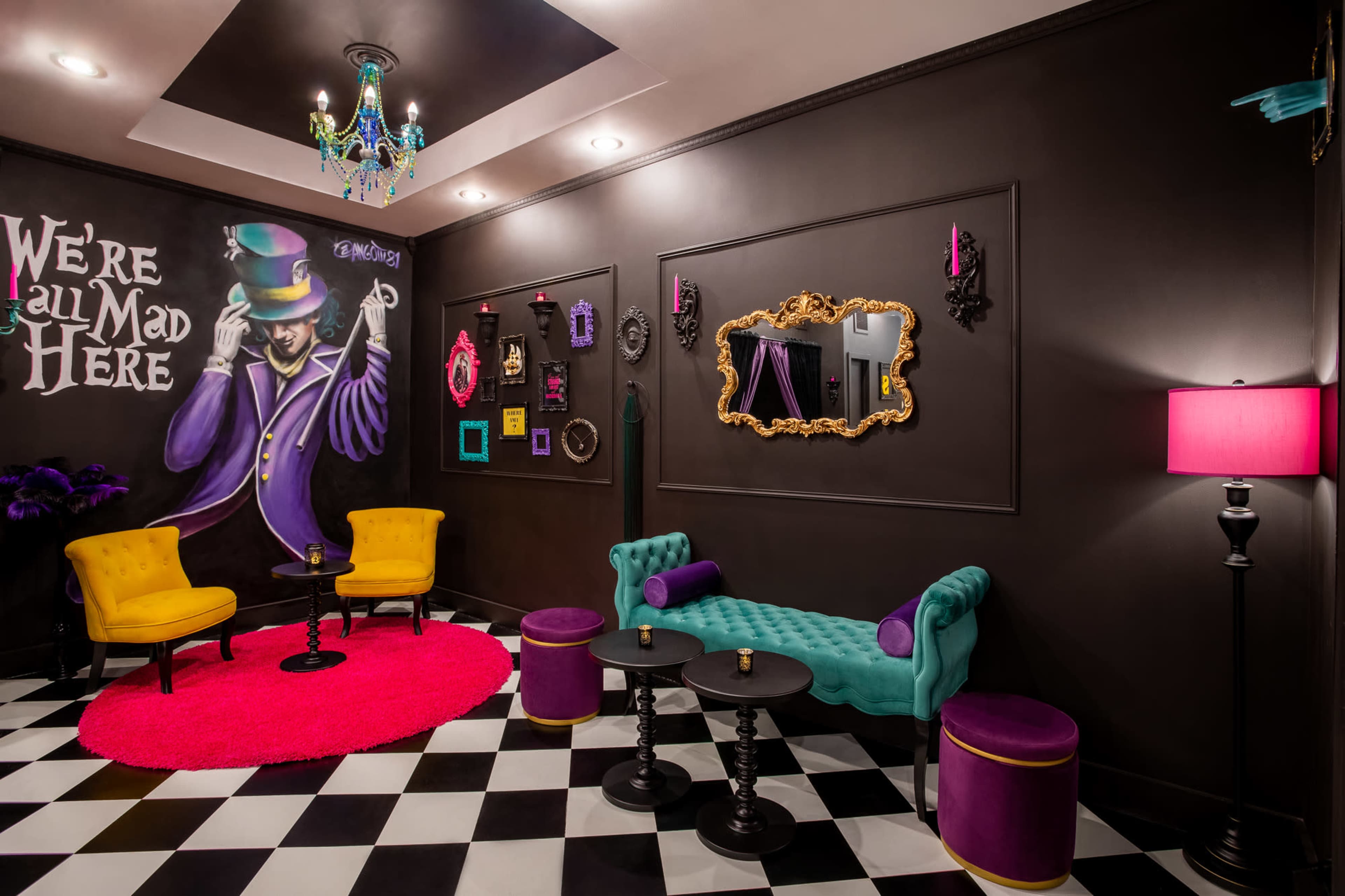 A vibrant room with a black and white checkered floor, featuring yellow and turquoise seating, and eclectic wall decor, including a whimsical mural and framed mirrors.
