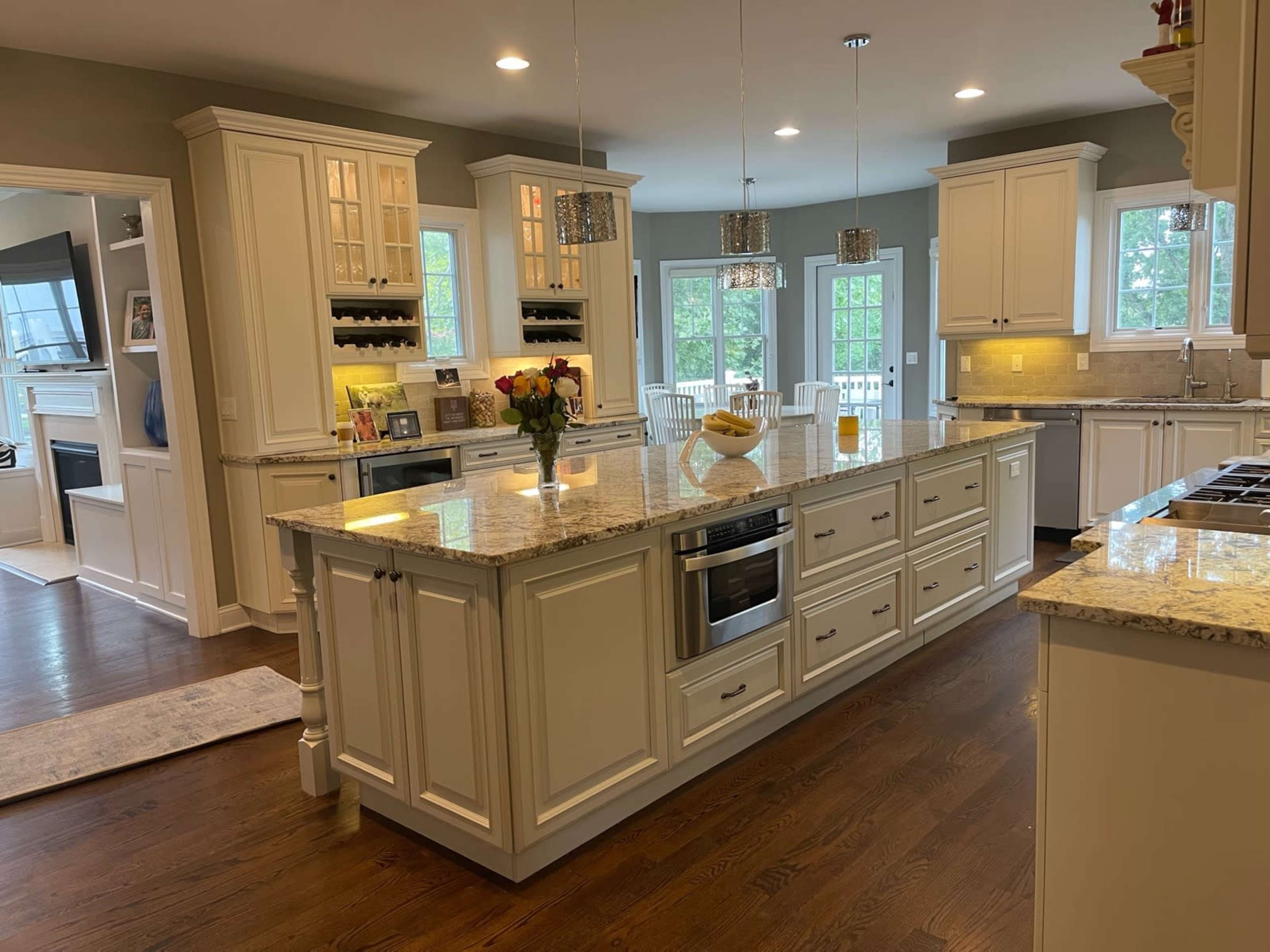 A spacious kitchen features white cabinetry, granite countertops, and stainless steel appliances, with a central island and breakfast area.