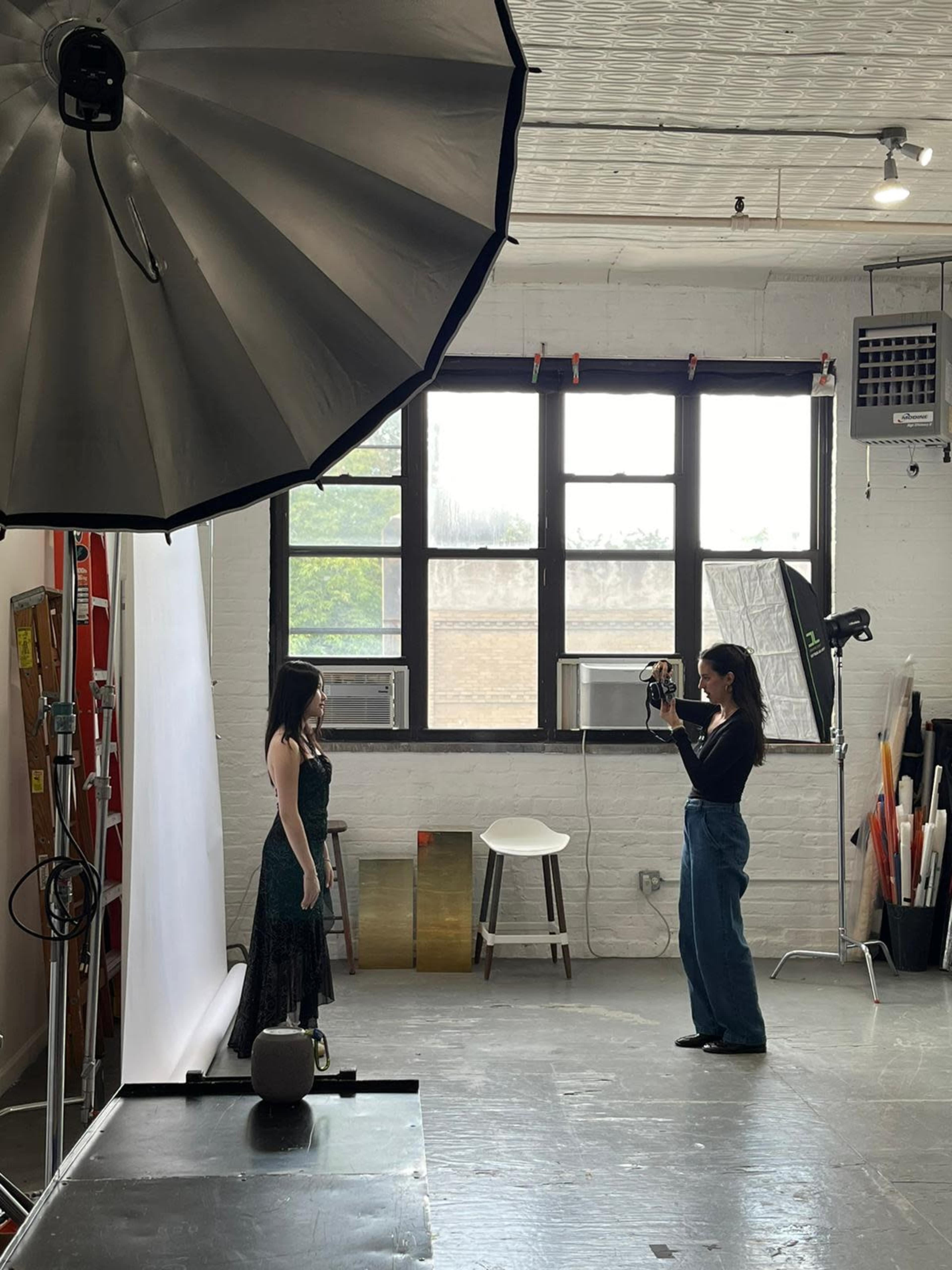 A photographer captures an image of a model wearing a formal dress in a well-lit studio.