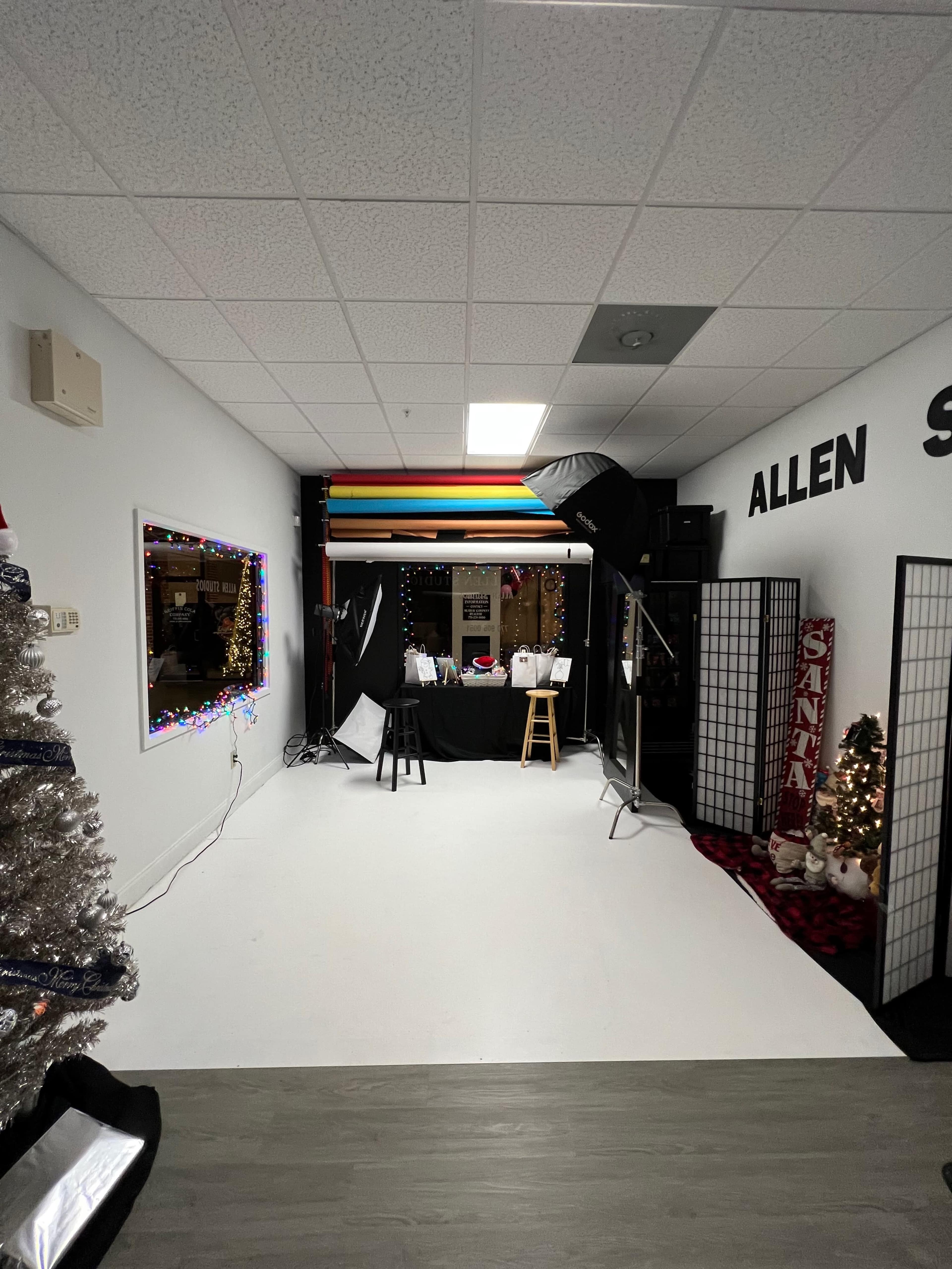 A photography studio with bright backdrops, a Christmas tree in the corner, and various props set up for a photo session.