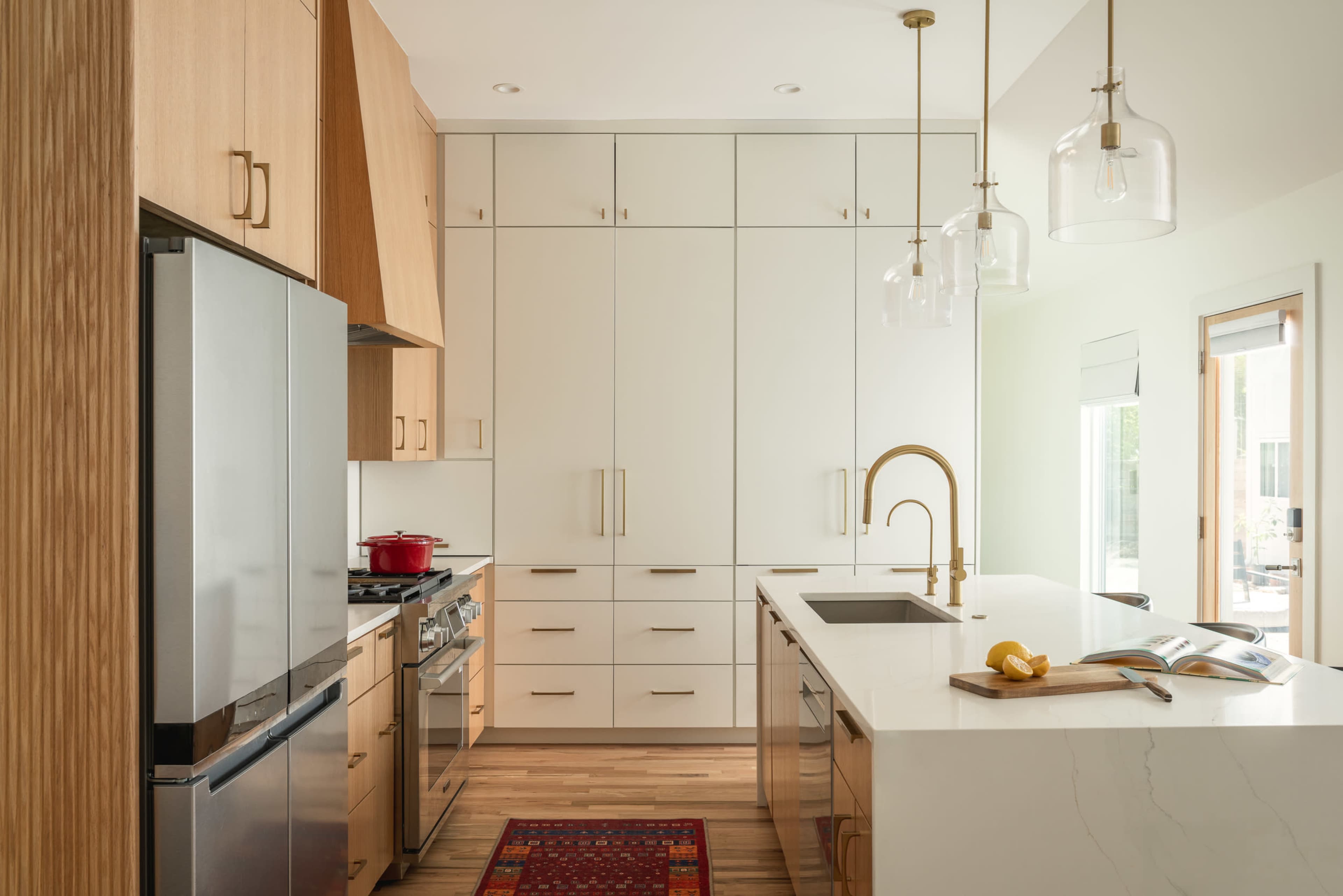 A modern kitchen features sleek cabinetry, stainless steel appliances, and an island with a white countertop and a sink.