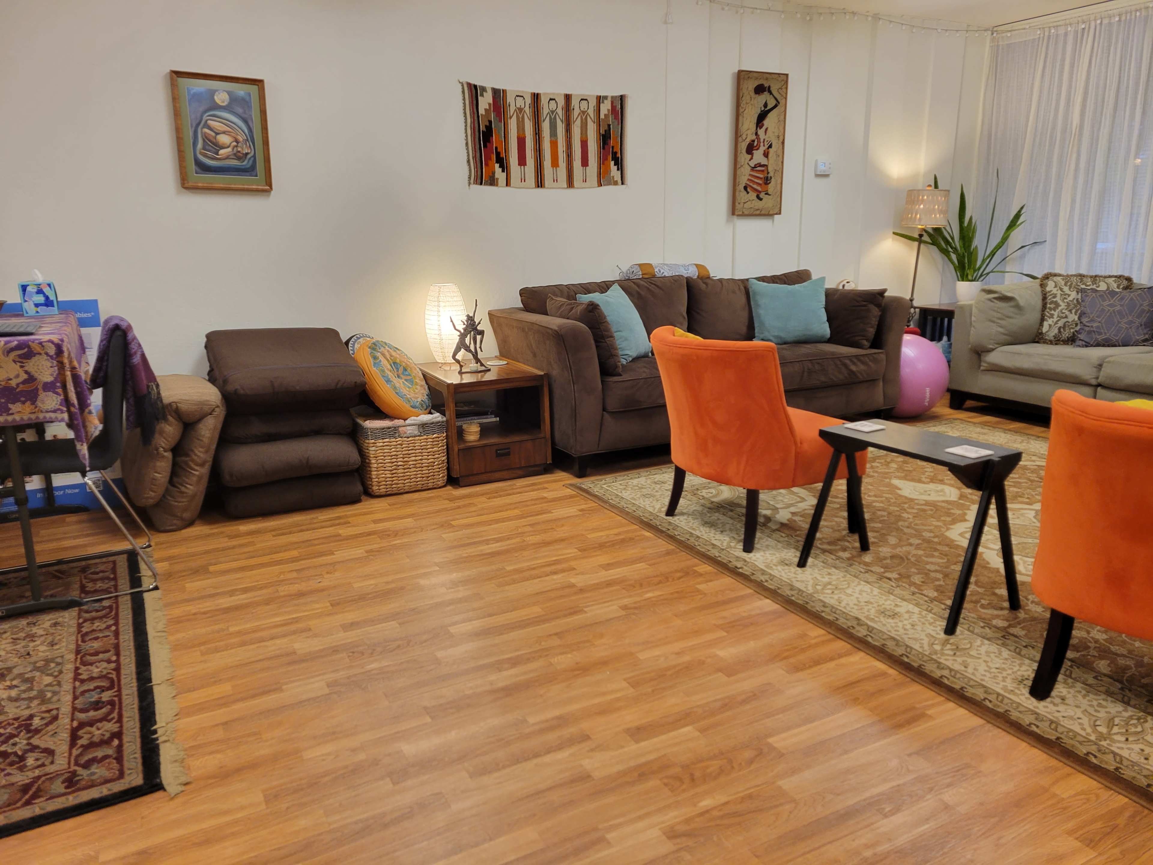 The living room features a combination of couches, accent chairs, a patterned rug, and decorative wall art.