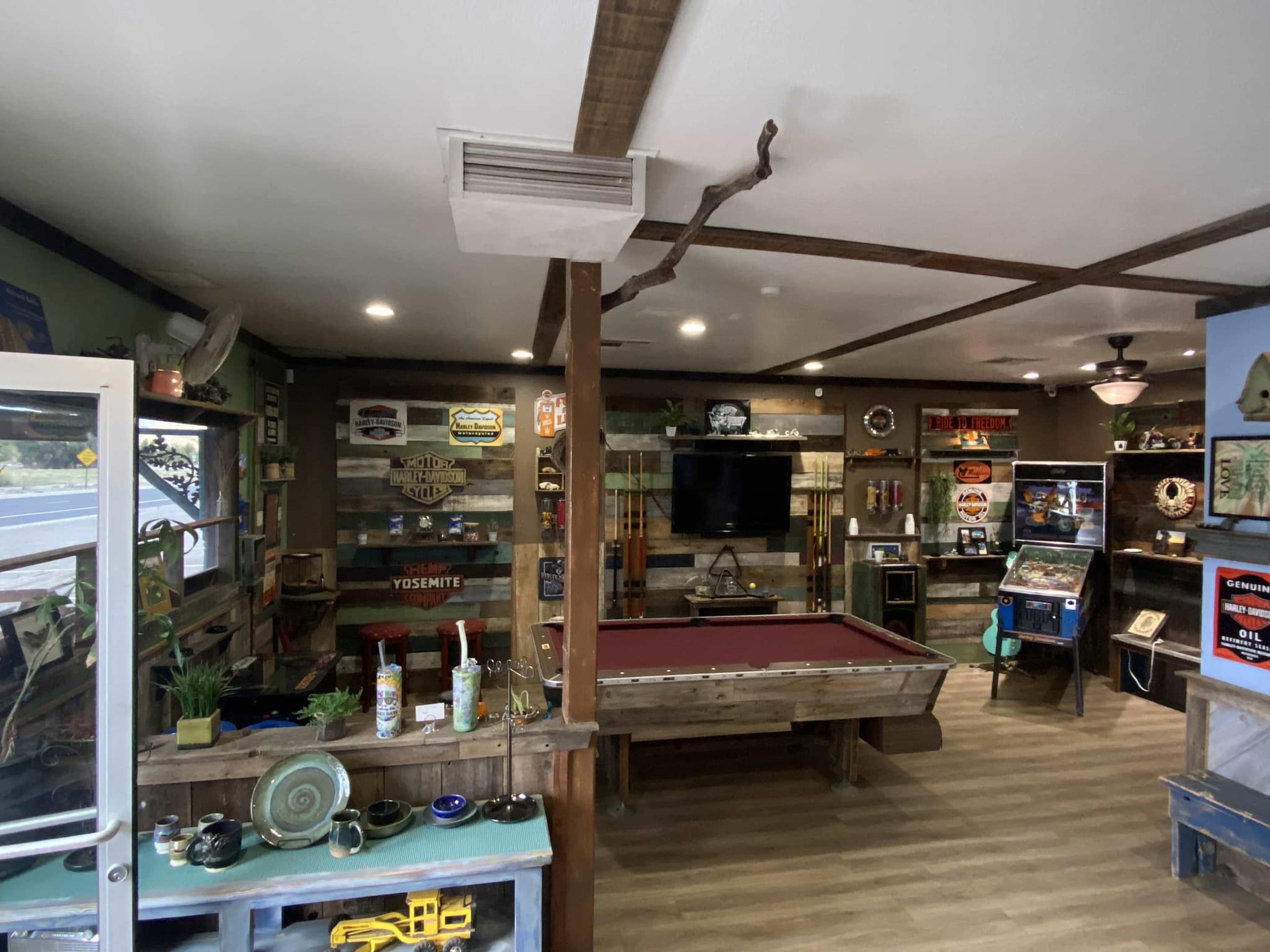 The interior of a recreational room features a pool table, a wall-mounted TV, and various vintage signs and decor.