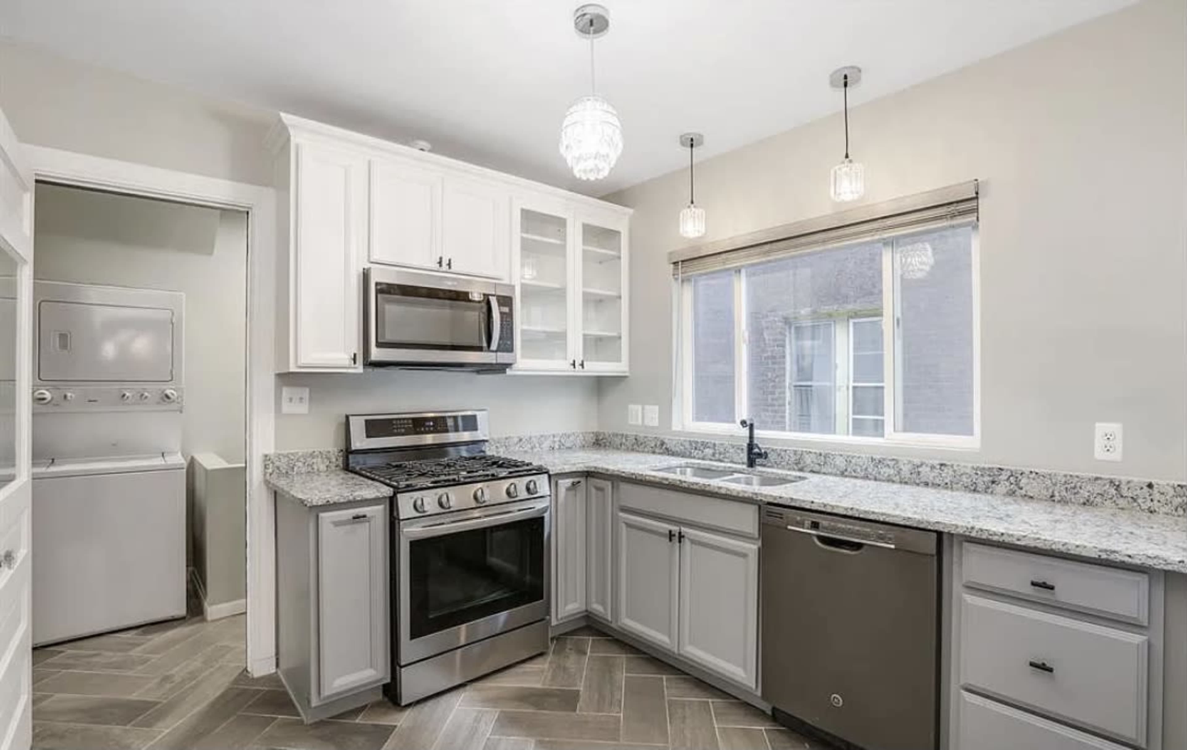 A modern kitchen features stainless steel appliances, a granite countertop, and a window above the sink.