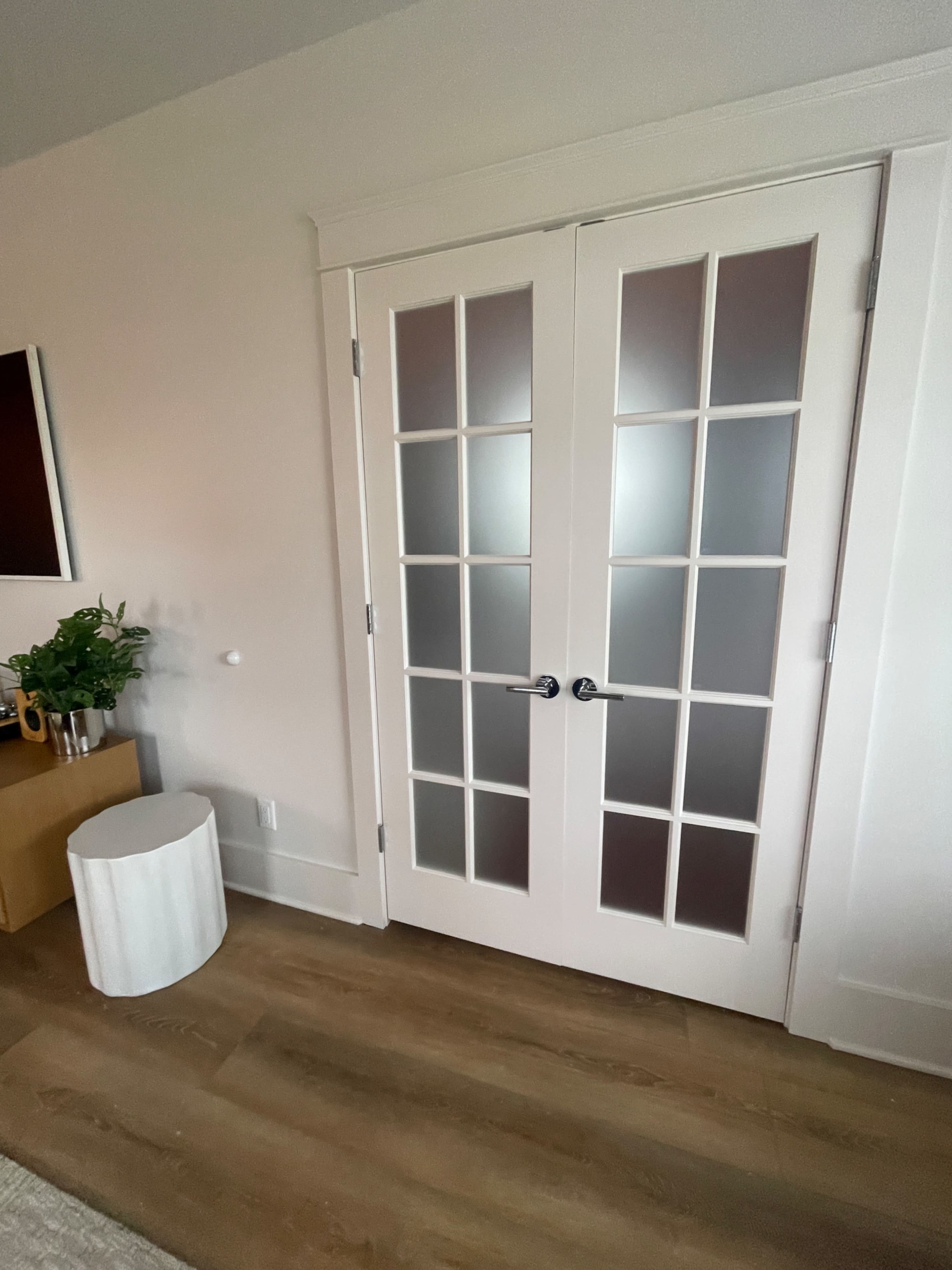A pair of white French doors with frosted glass panels in a contemporary interior space.