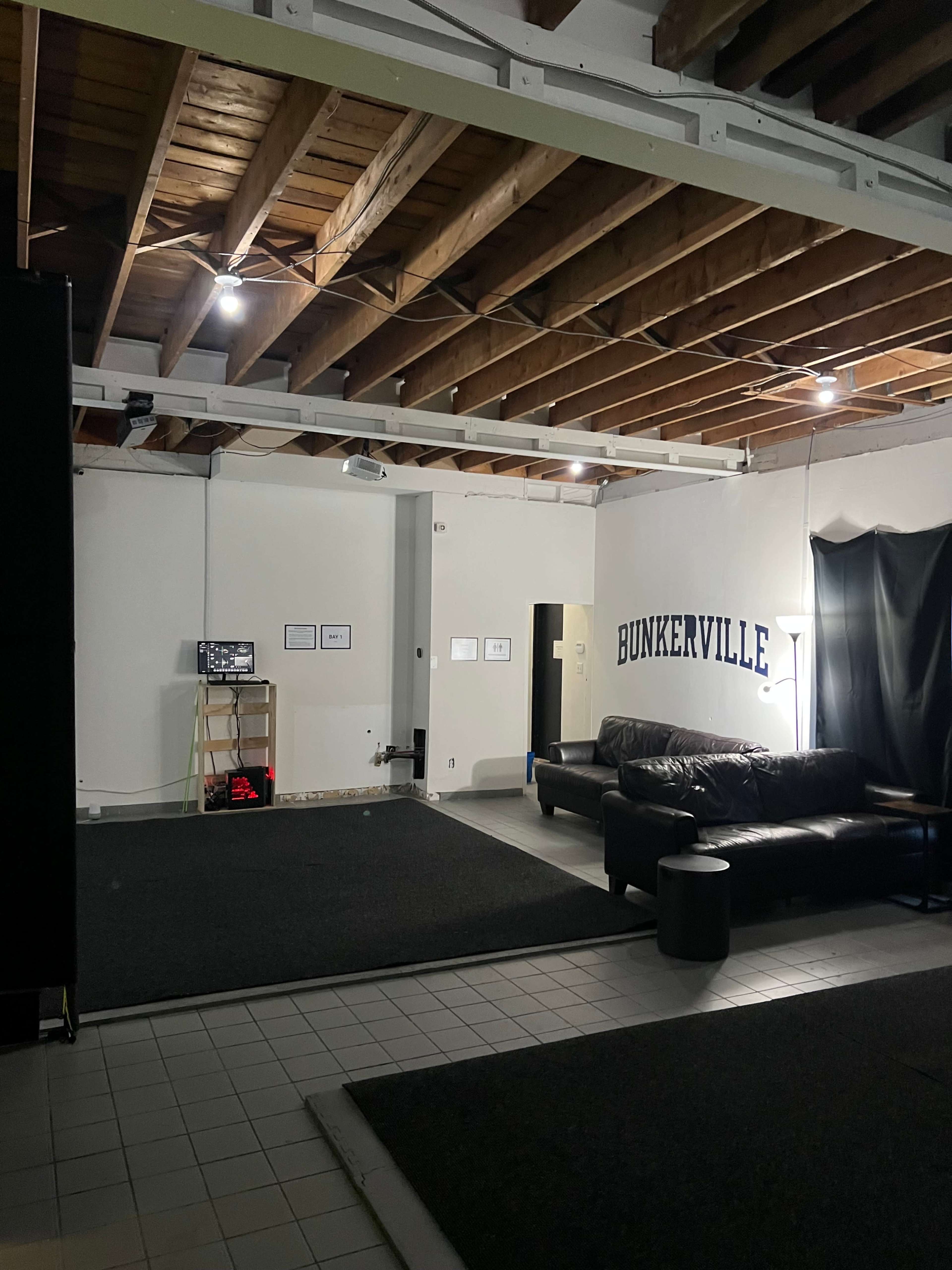 The image shows an interior space with a couch, dark carpet, and a wall labeled "BUNKERVILLE."