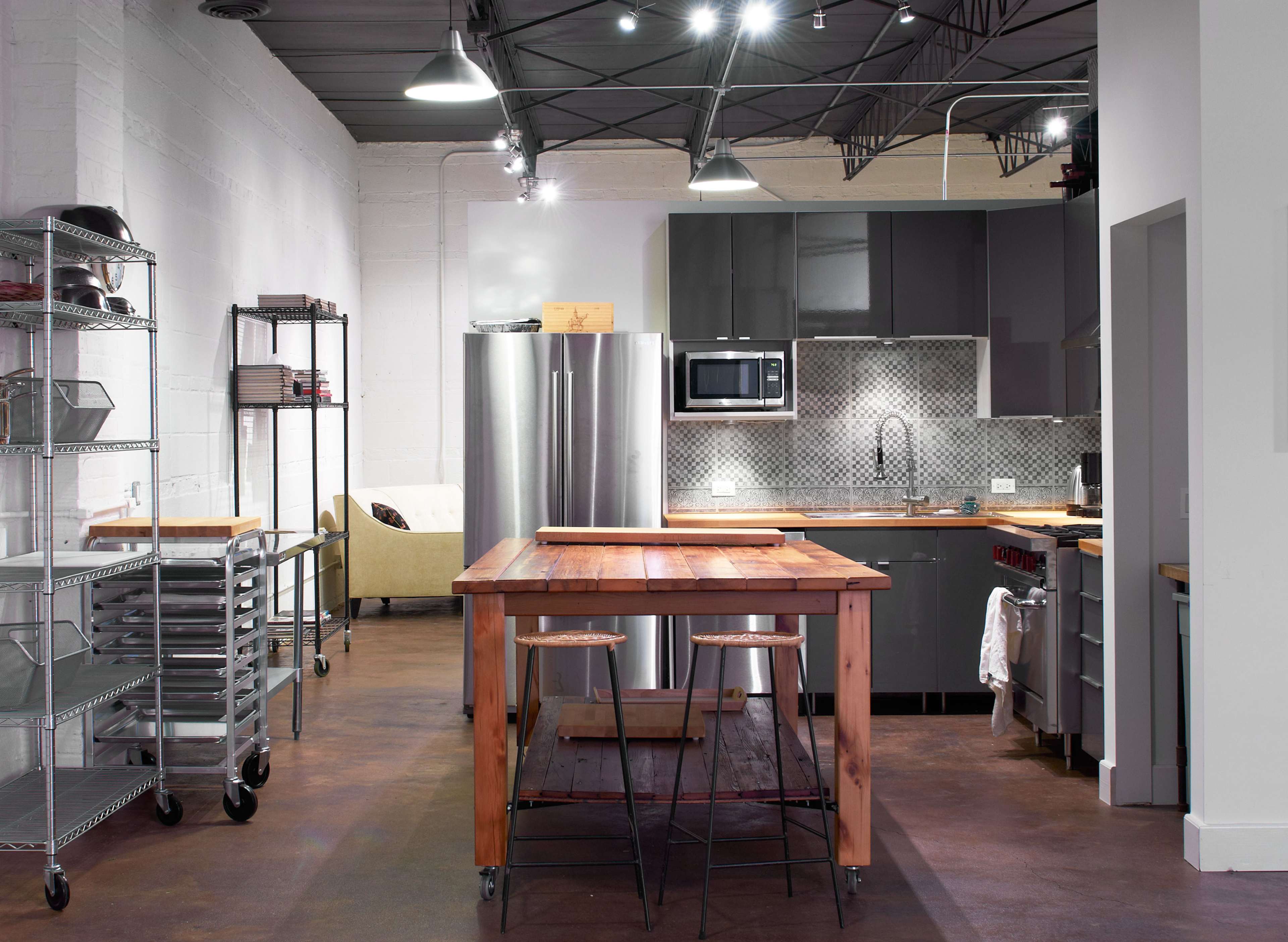 A modern kitchen with stainless steel appliances, a wooden island, and open shelving.