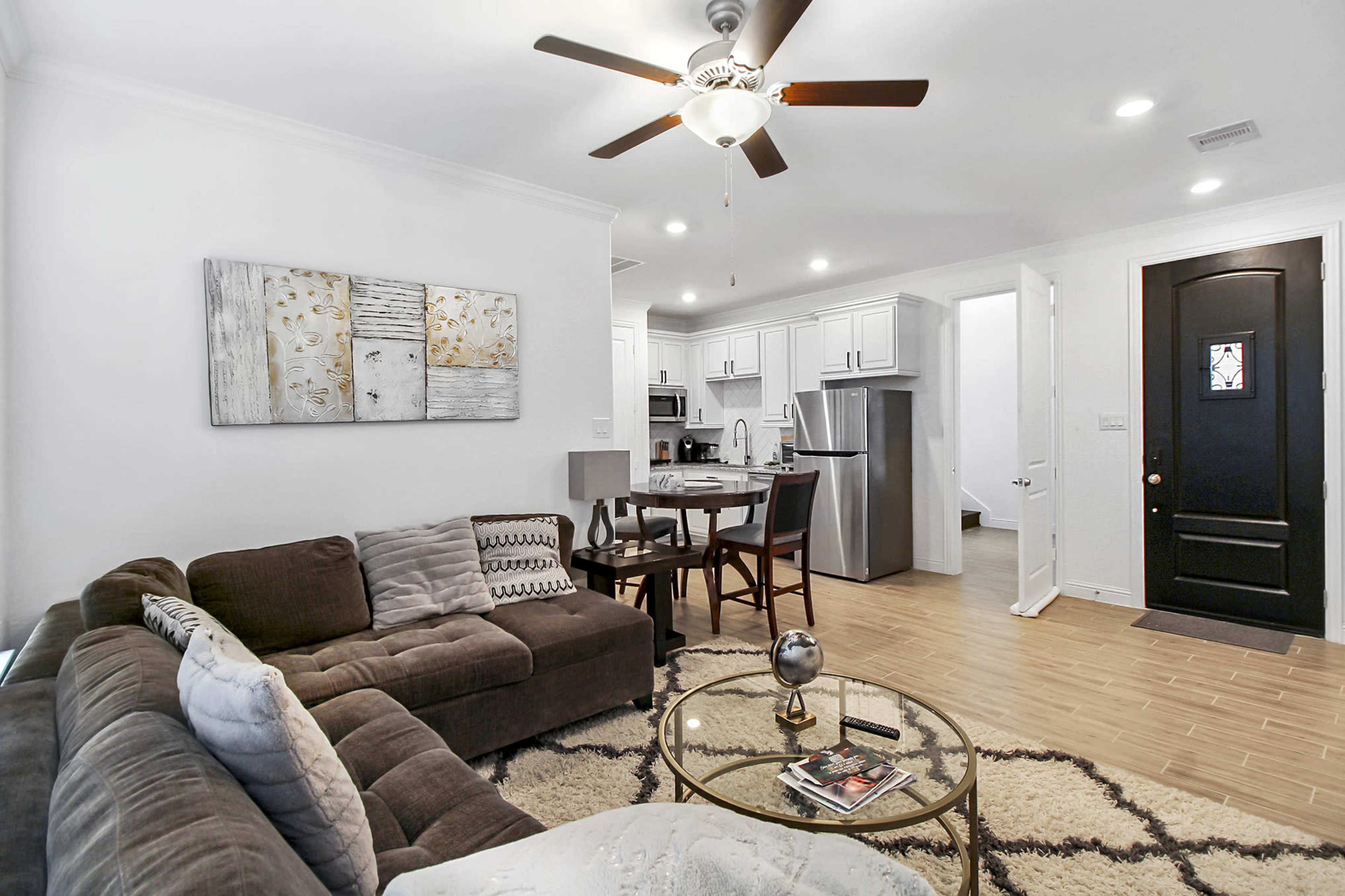 A modern living room with a brown sectional sofa, a coffee table, and a dining area in an open-concept layout.