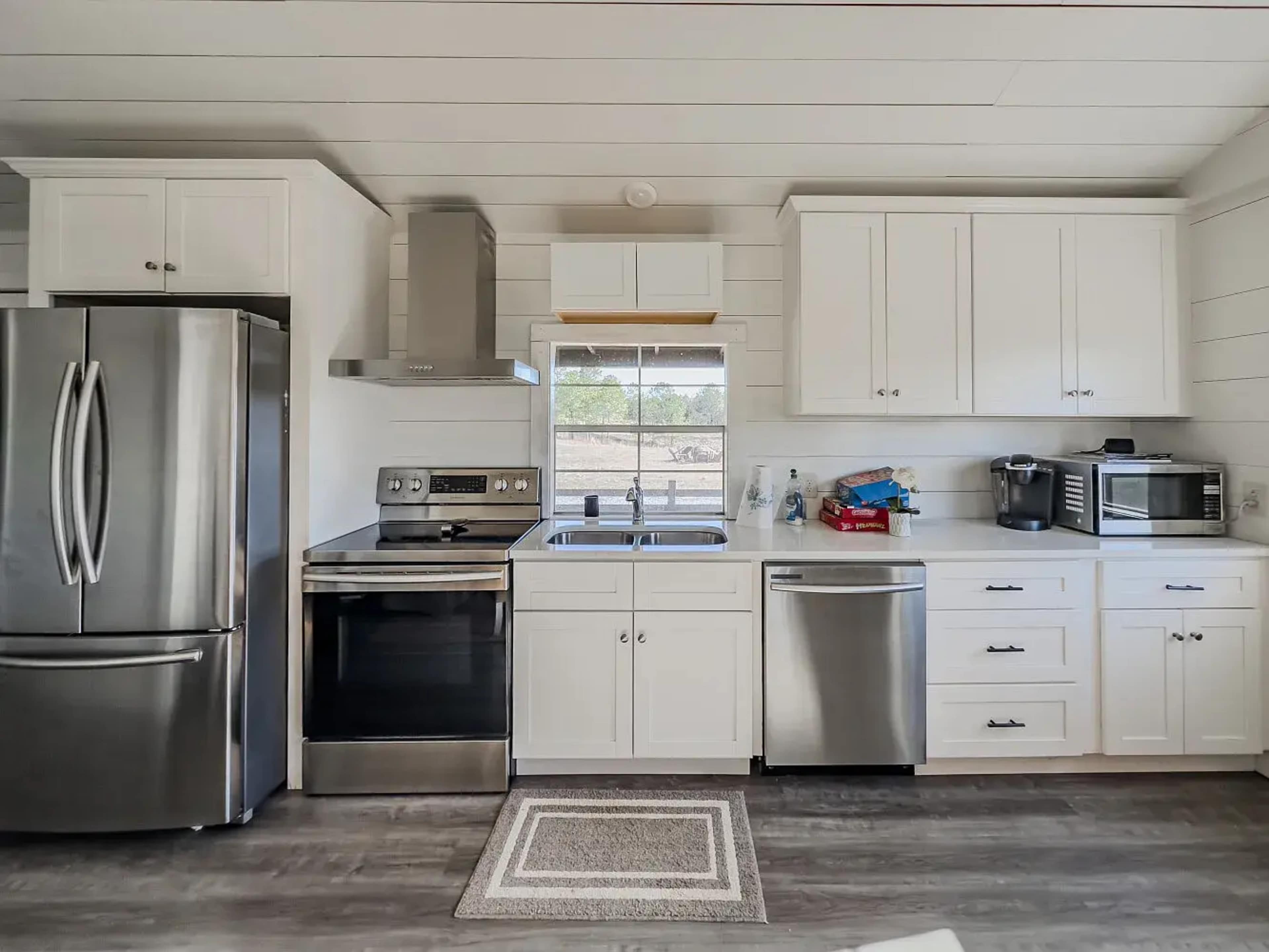 A modern kitchen featuring stainless steel appliances, white cabinetry, and a window above the sink.