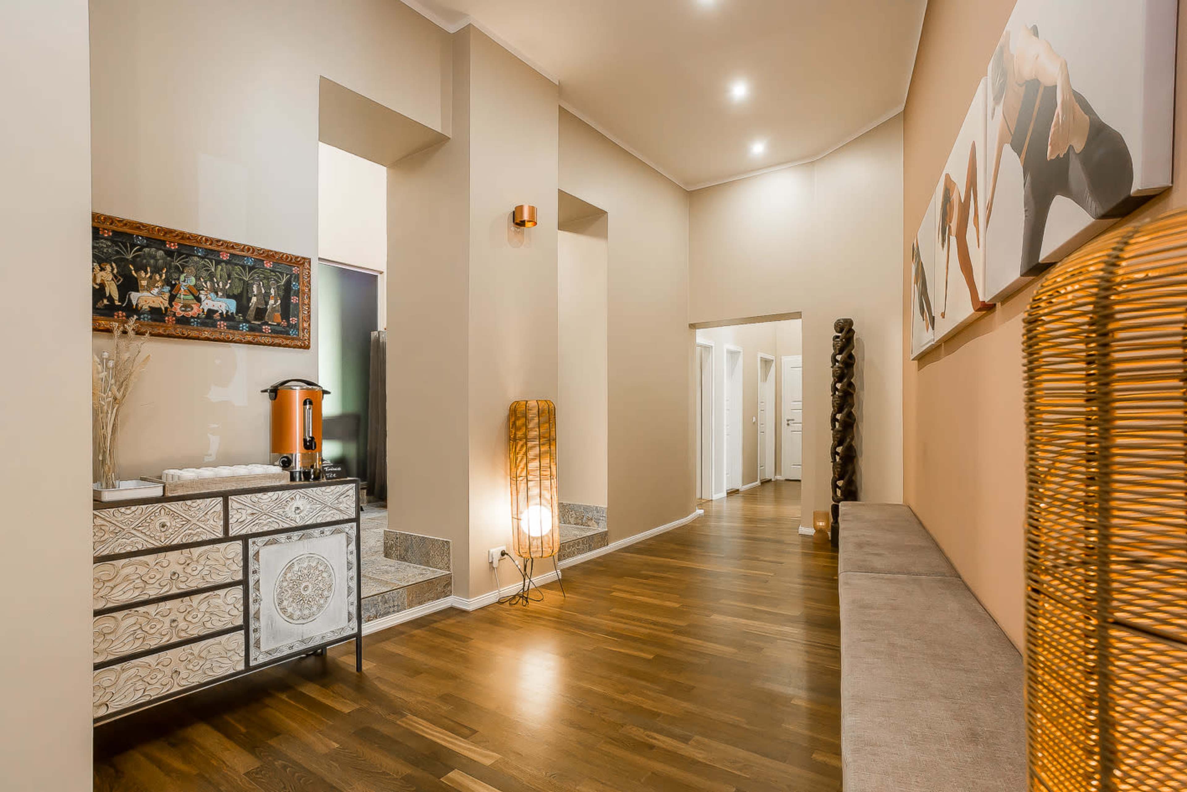 A hallway featuring a decorative console table, a bench, and wall art, with soft lighting and wooden flooring.