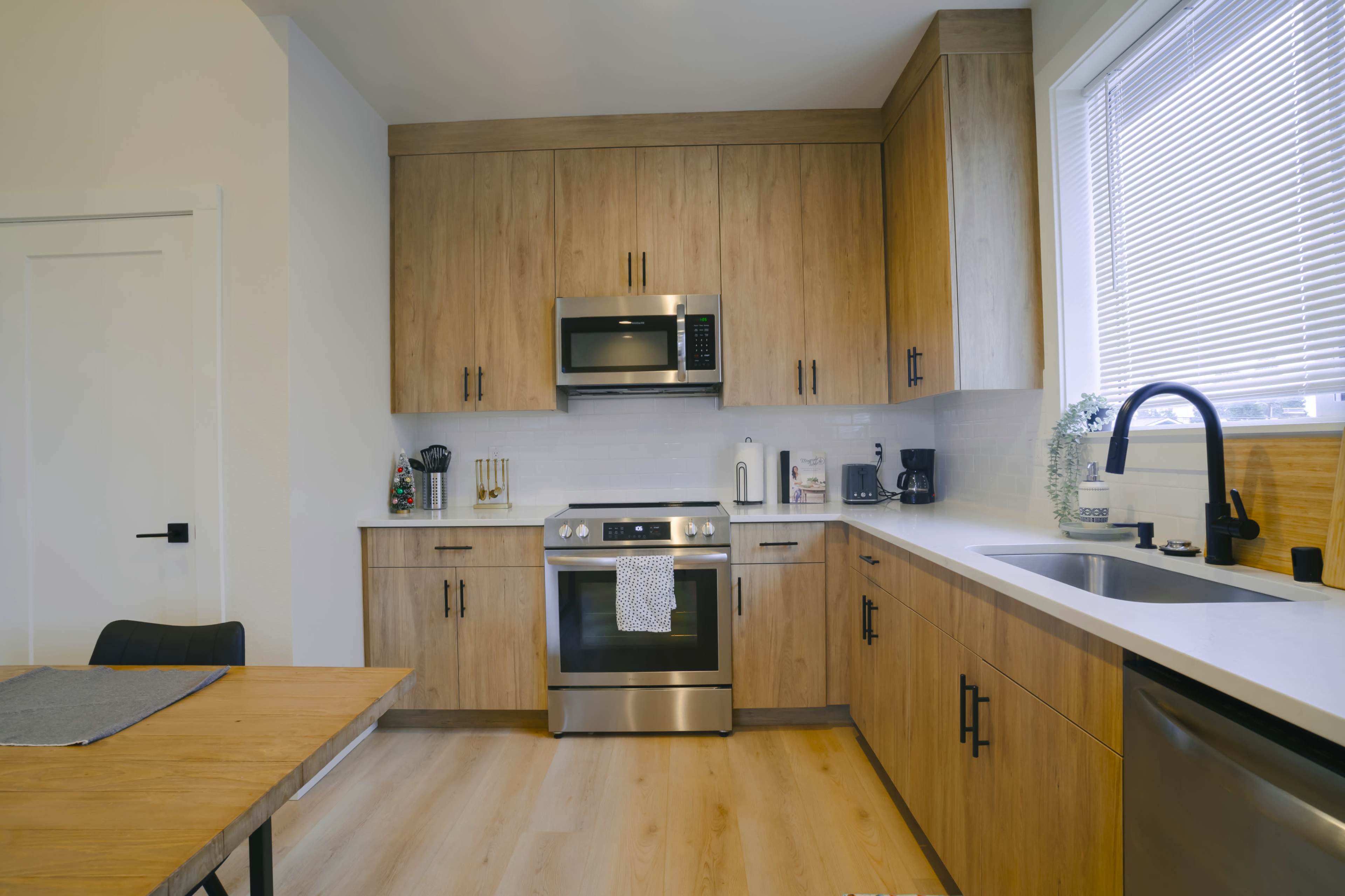 A modern kitchen features wooden cabinetry, stainless steel appliances, and a dining table.