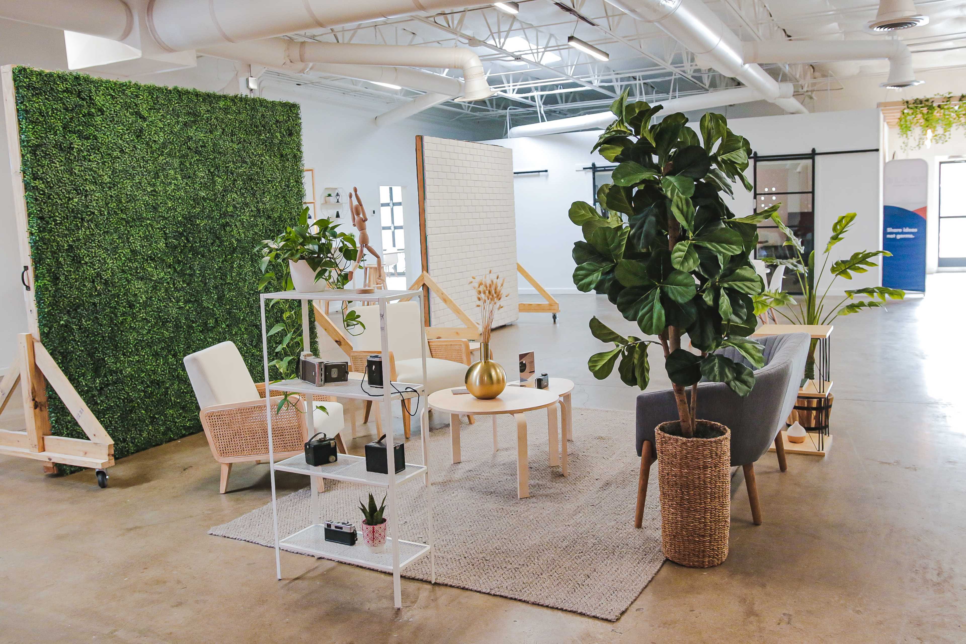 A modern, minimalist lounge area featuring a green wall, various seating options, and decorative plants.