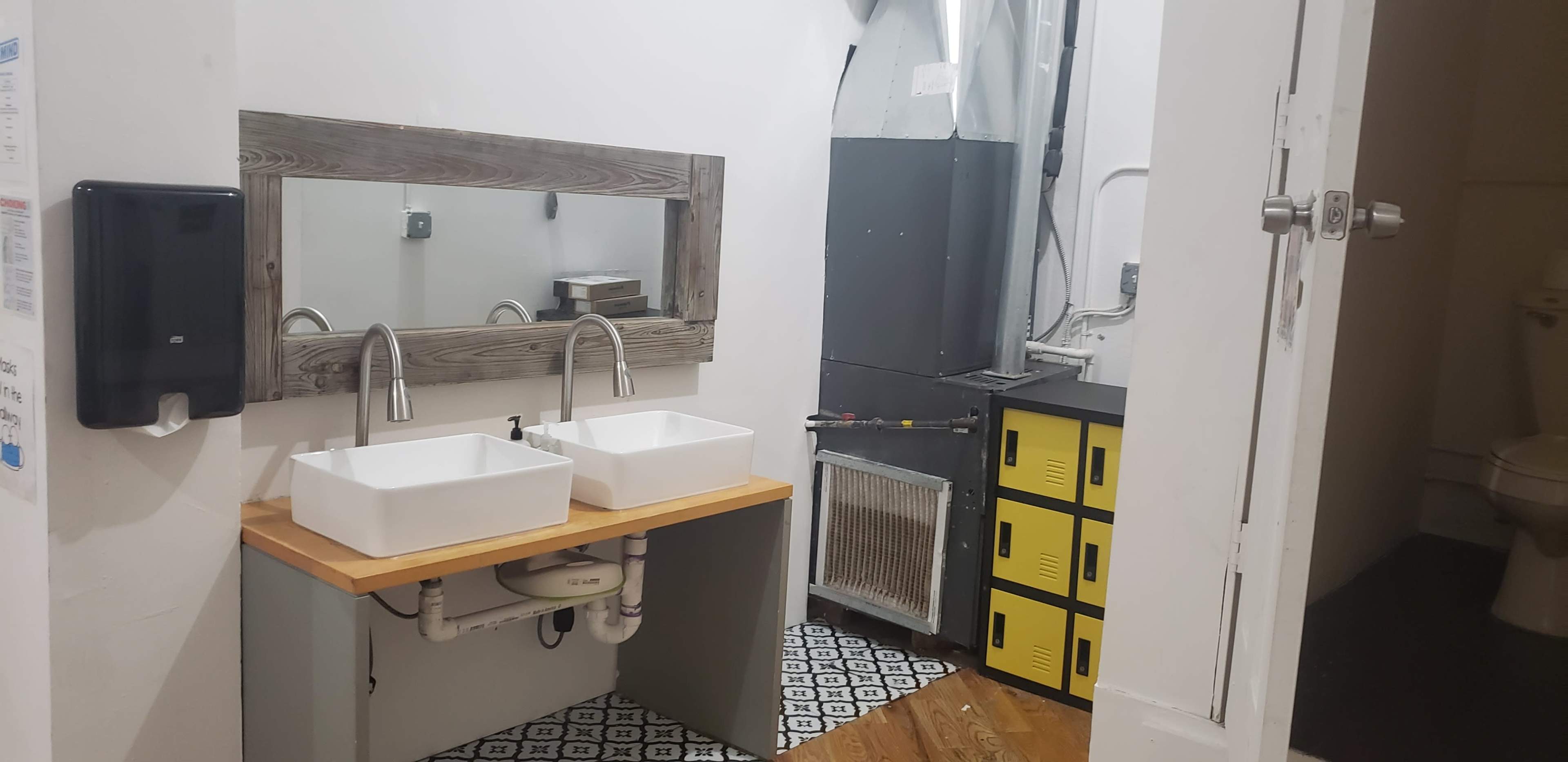A bathroom features two rectangular sinks on a wooden countertop, with a mirror above and a black and yellow cabinet to the right.
