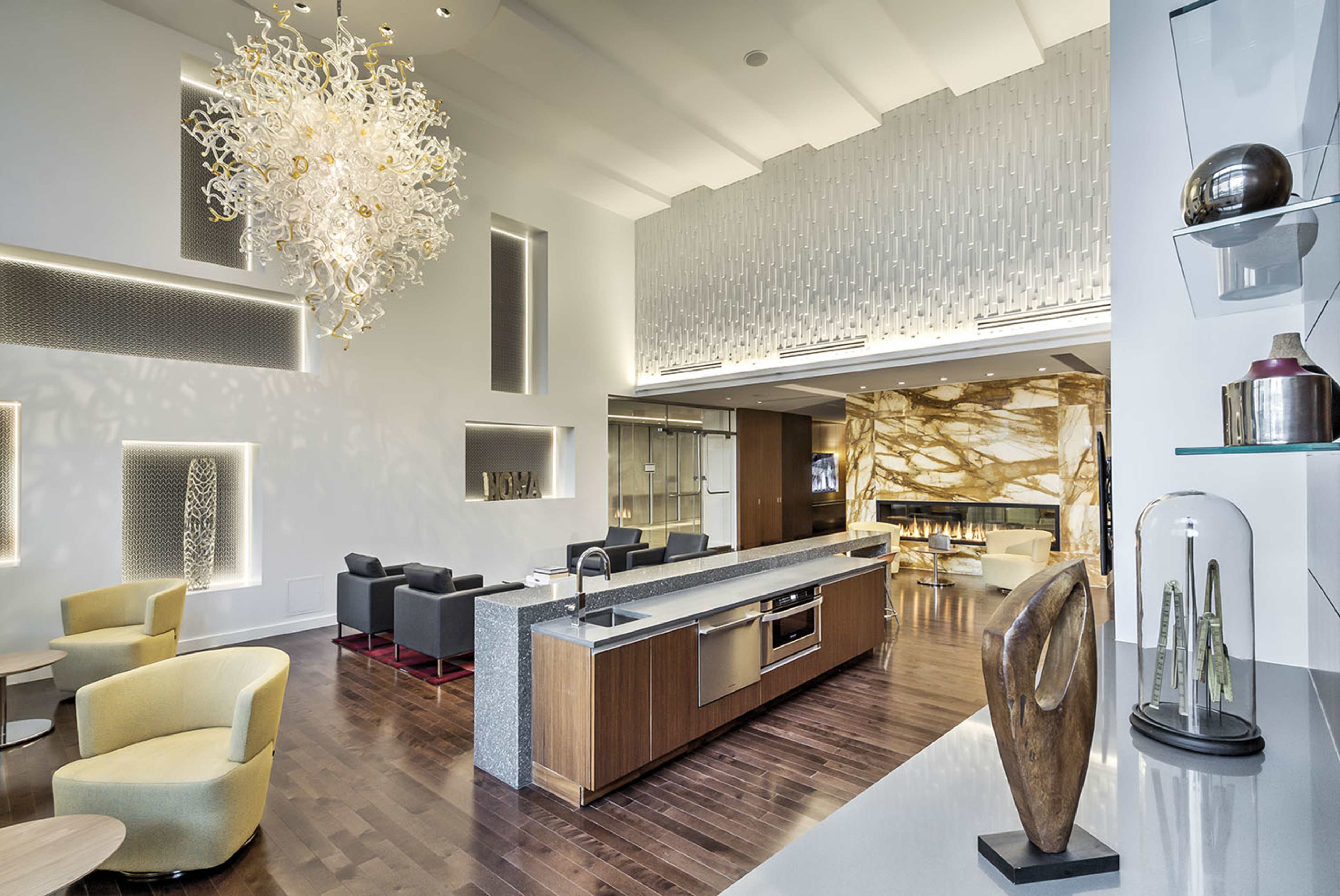 A modern lounge area featuring a large kitchen island, stylish furniture, and an eye-catching chandelier.