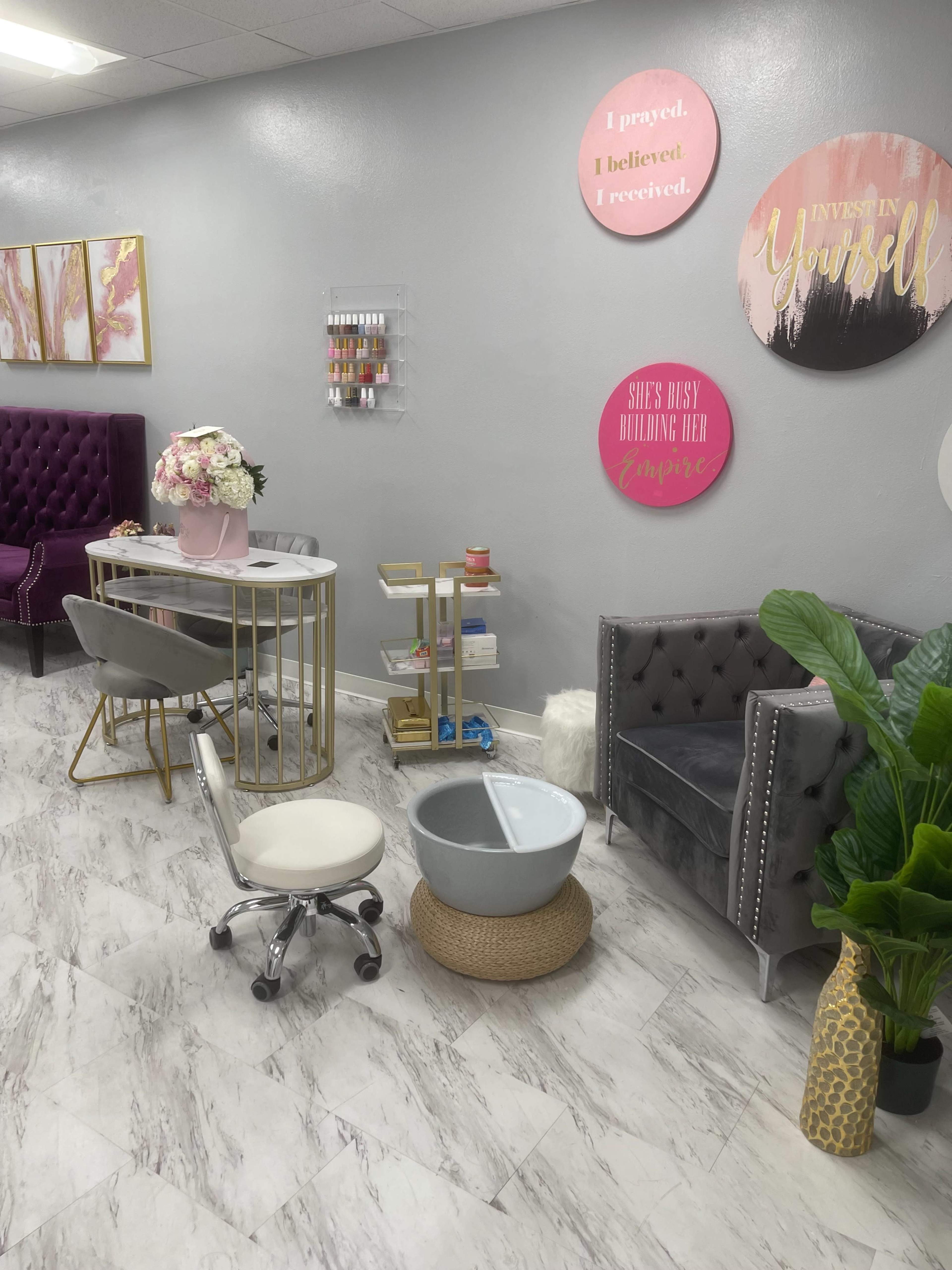A beauty salon interior featuring a reception desk, a comfortable chair, a pedicure station with a basin, and decorative wall art.