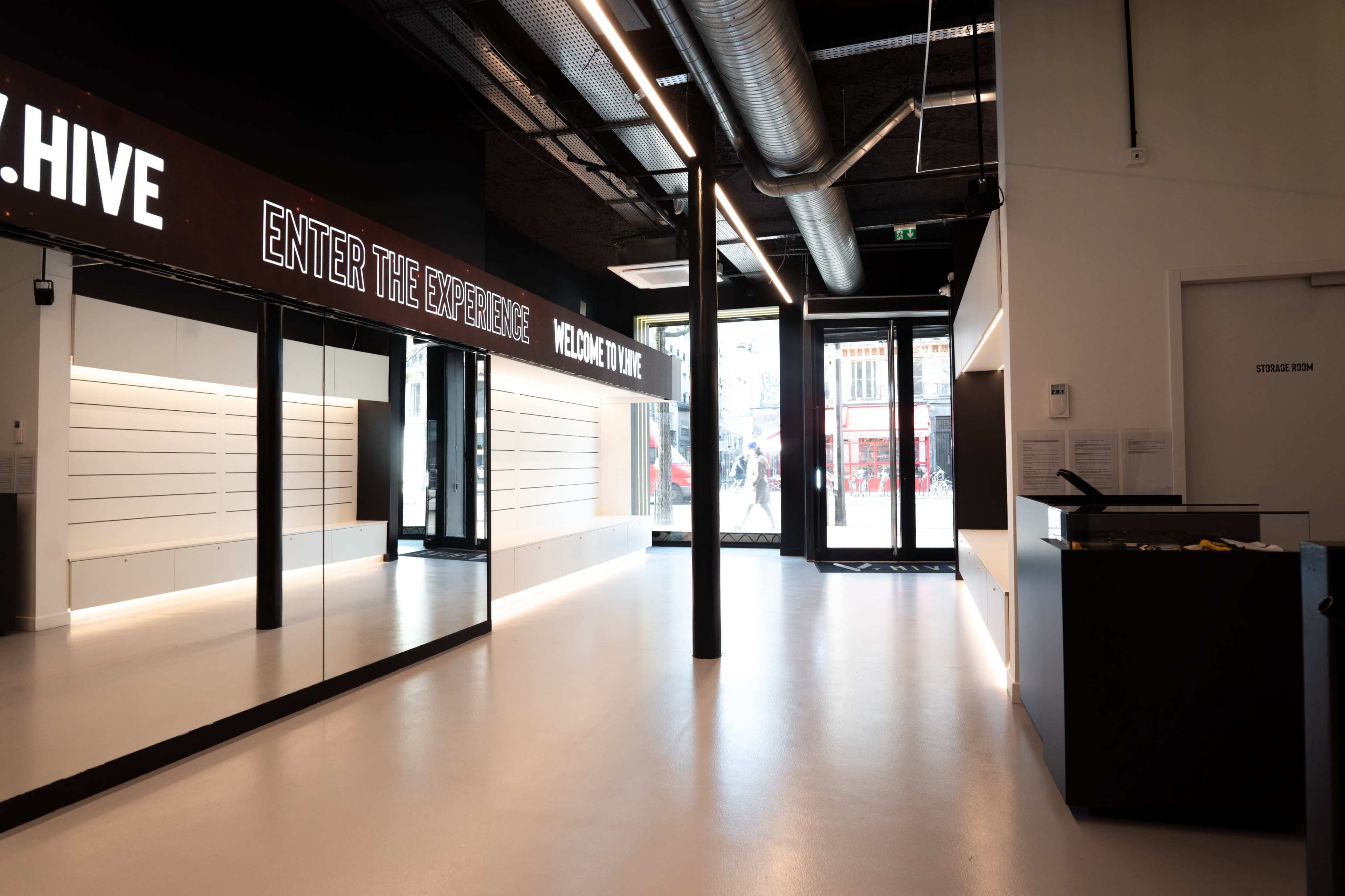 The image shows a modern, sleek interior of a retail space featuring white walls, polished flooring, and large windows with illuminated signage.