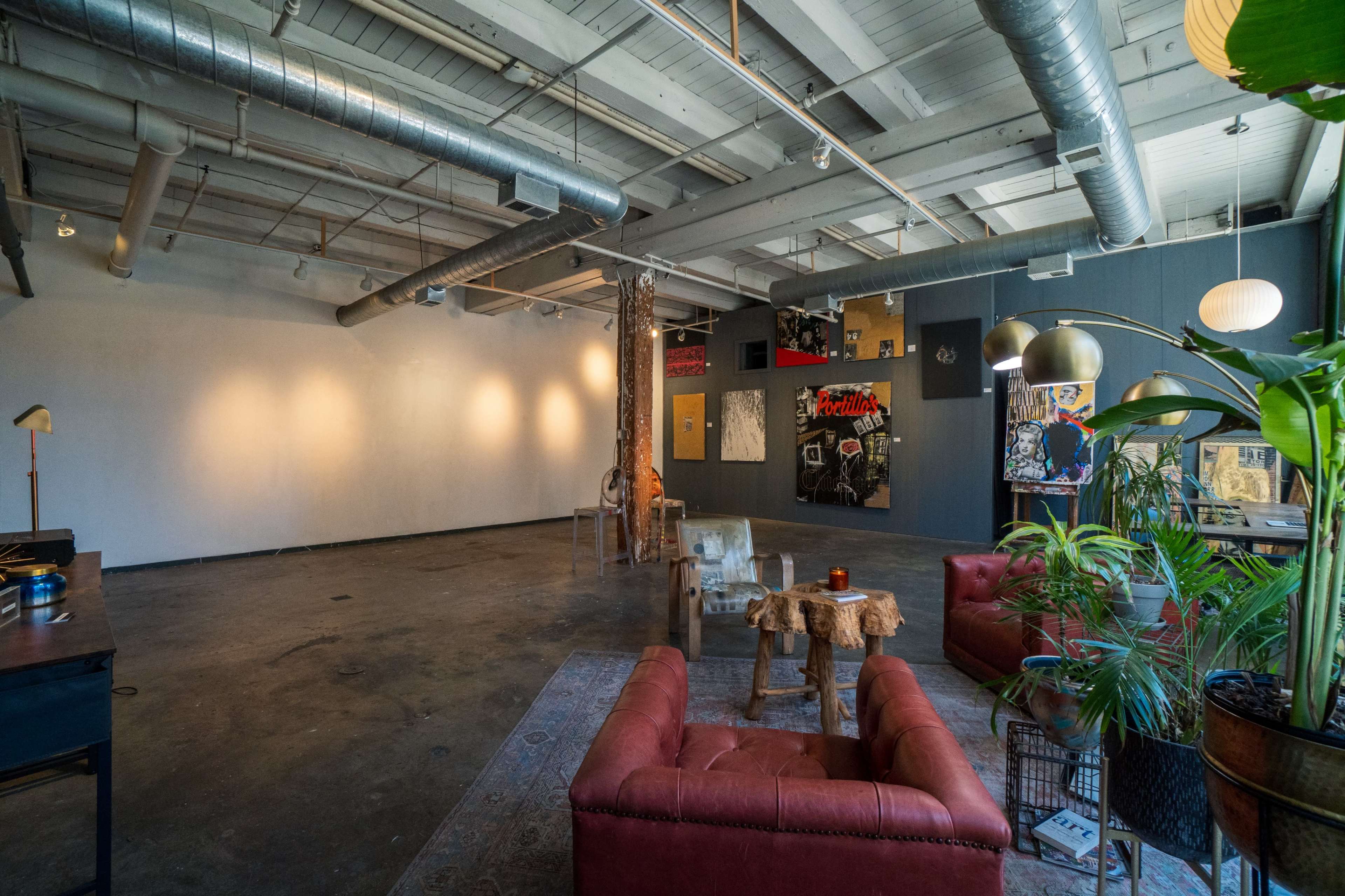 An industrial-style interior with a mix of comfortable seating, artwork on the walls, and a well-lit, open space.