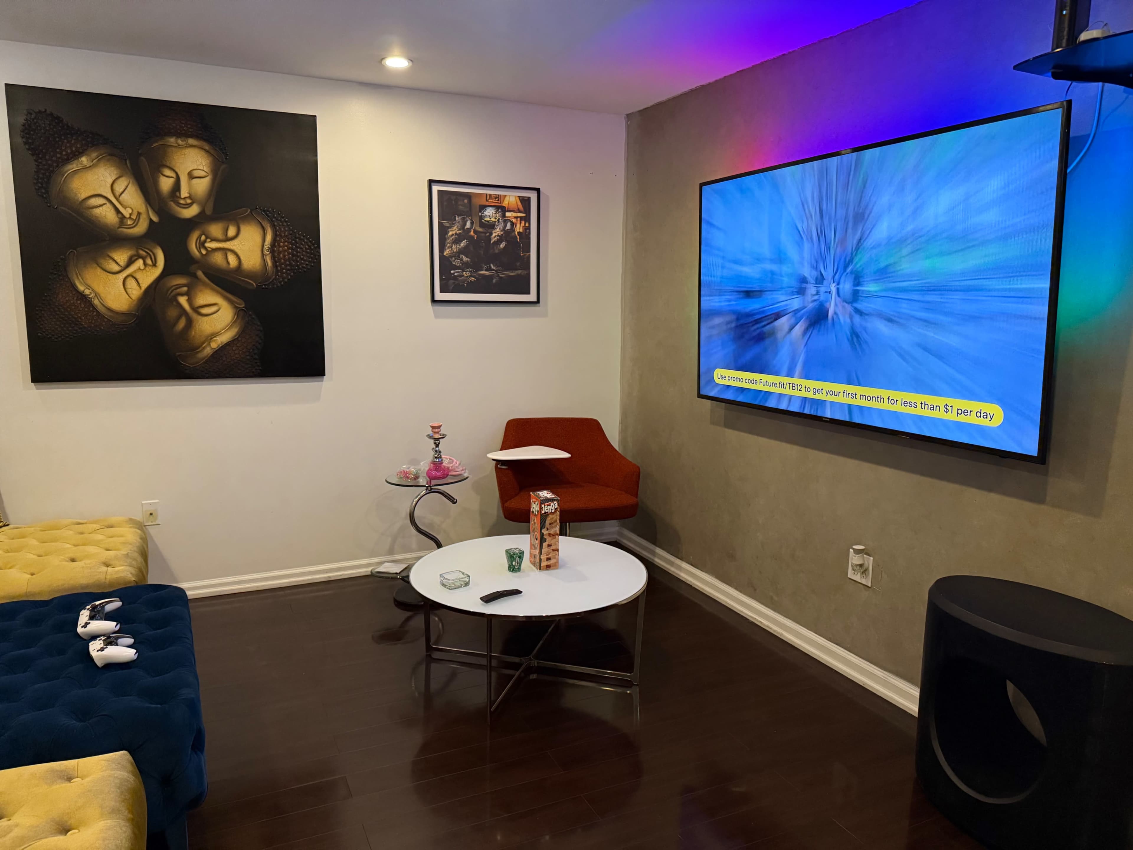 The image showcases a modern living room with a large television mounted on the wall, a coffee table, a red chair, and a couch with colorful cushions.
