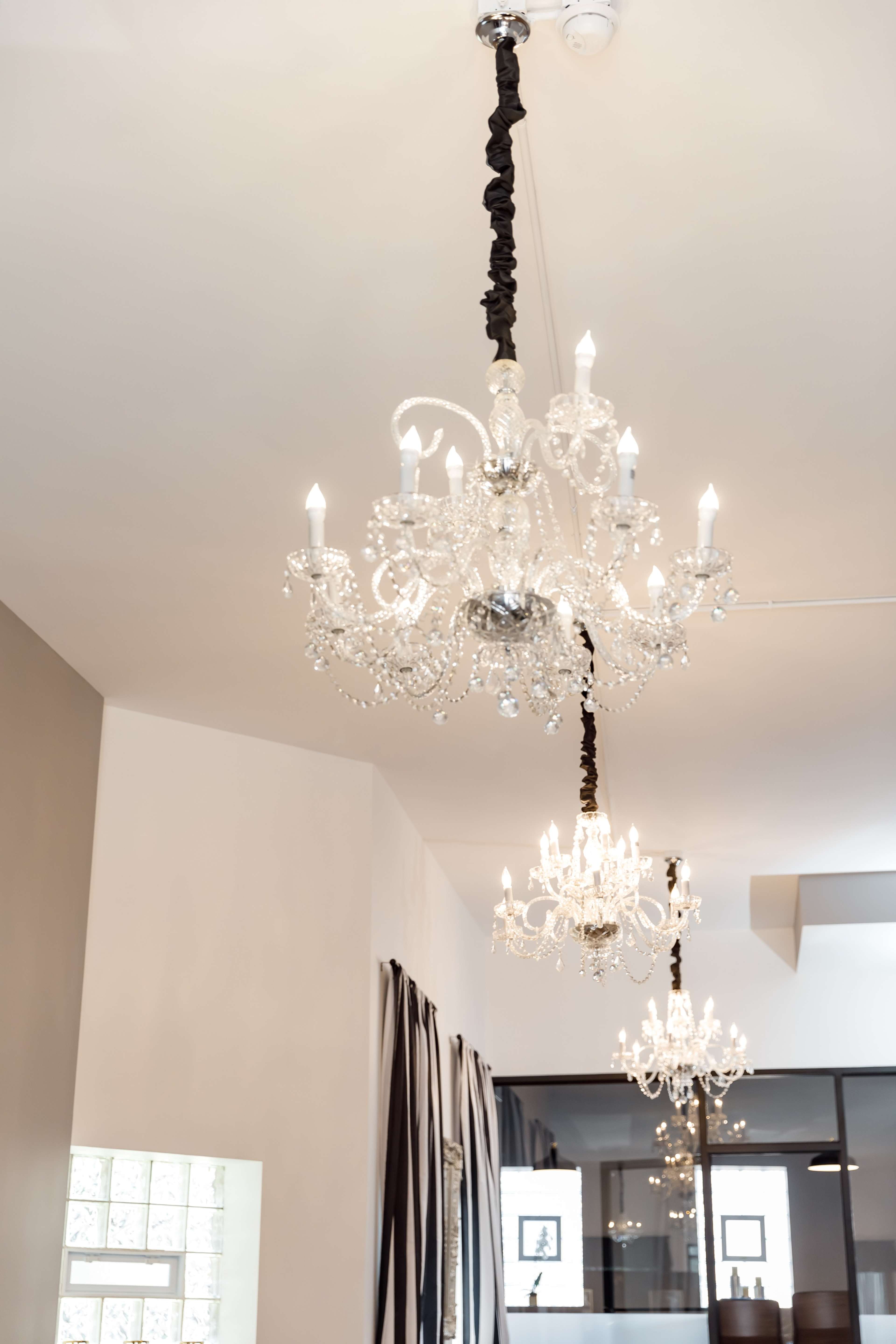 Several ornate chandeliers hanging from the ceiling of a modern interior space.