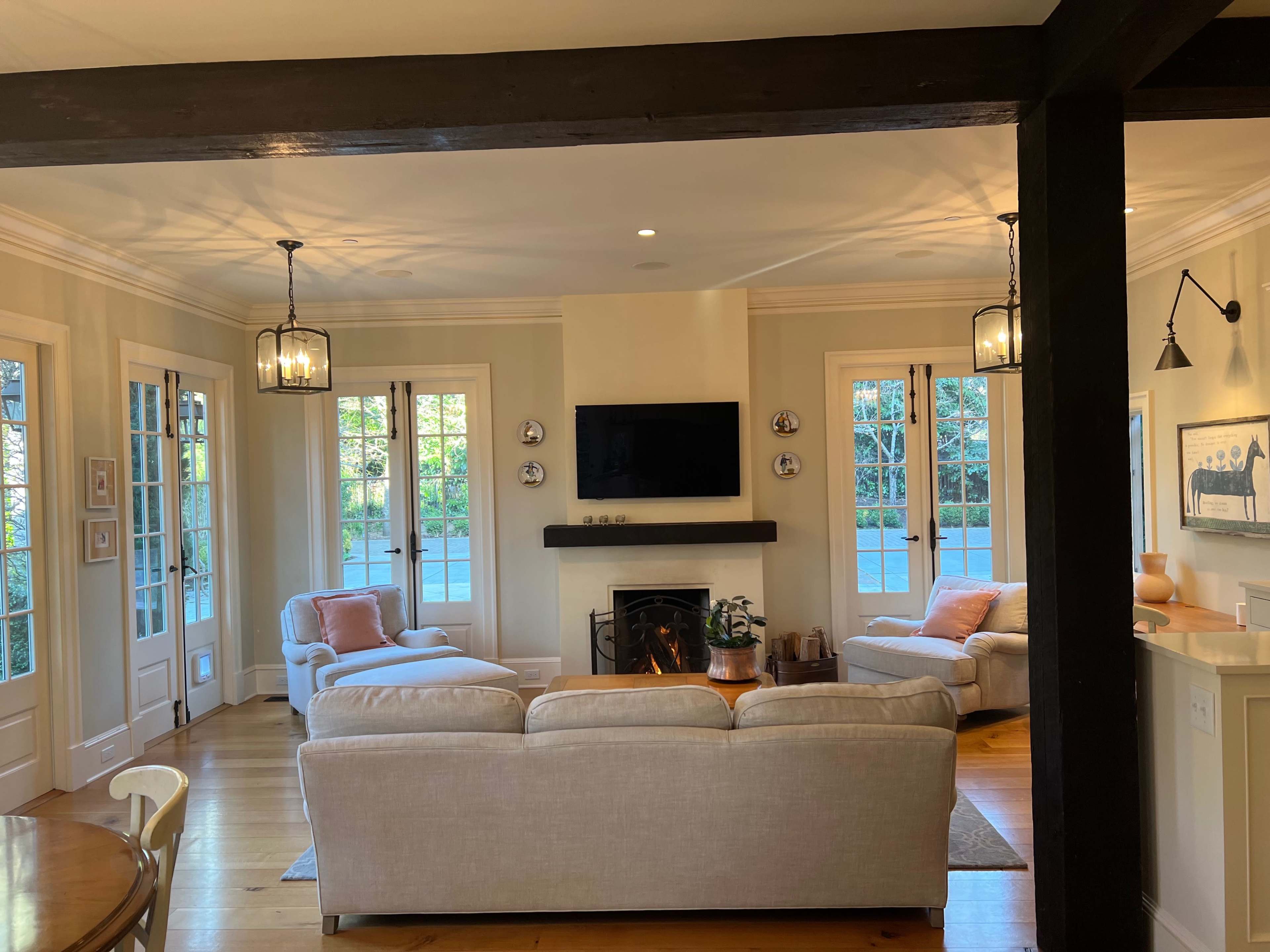 A well-lit living room with two seating areas, a fireplace, and large windows allowing natural light to enter.