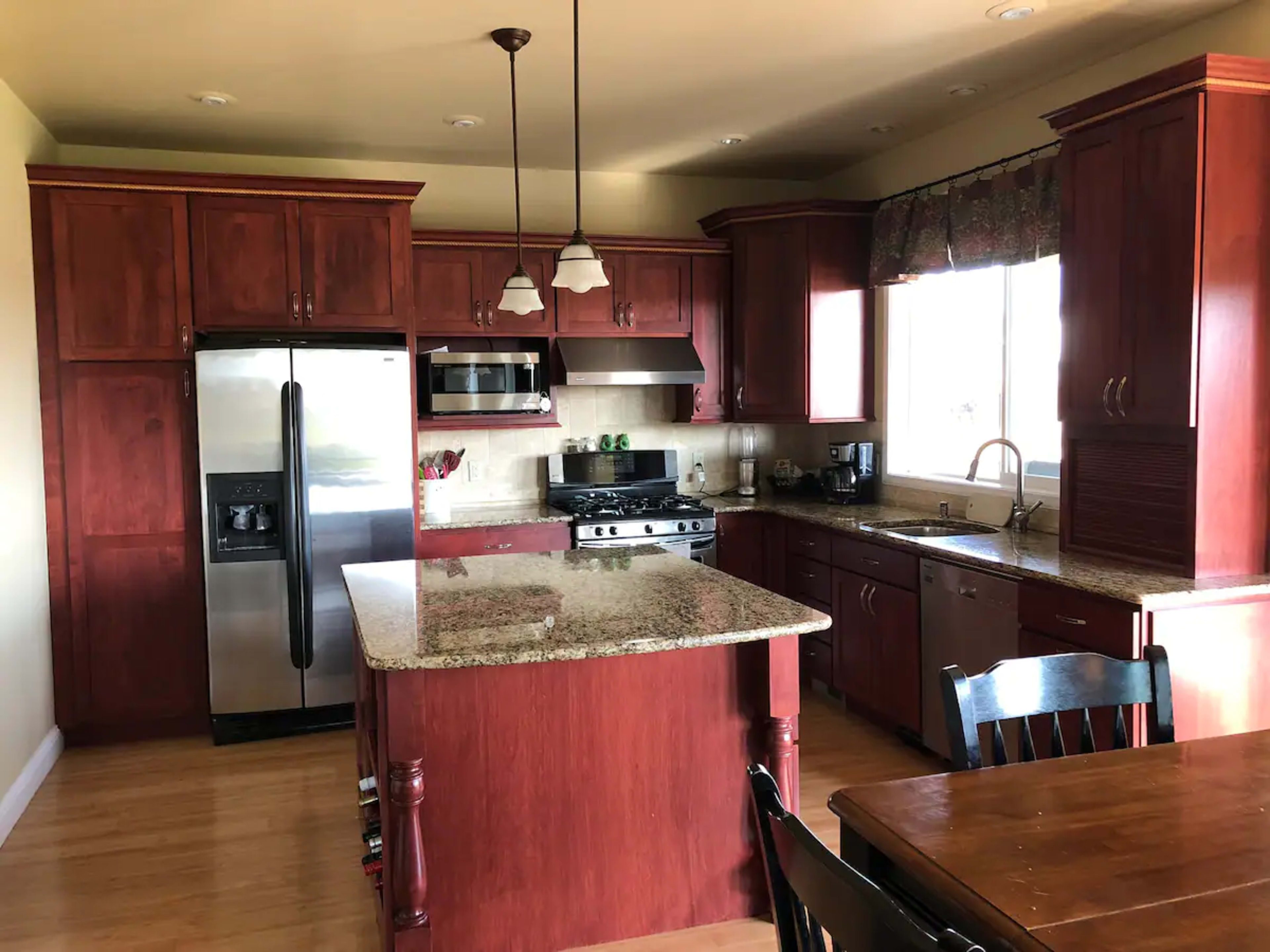 The image shows a kitchen with wooden cabinets, granite countertops, and stainless steel appliances.