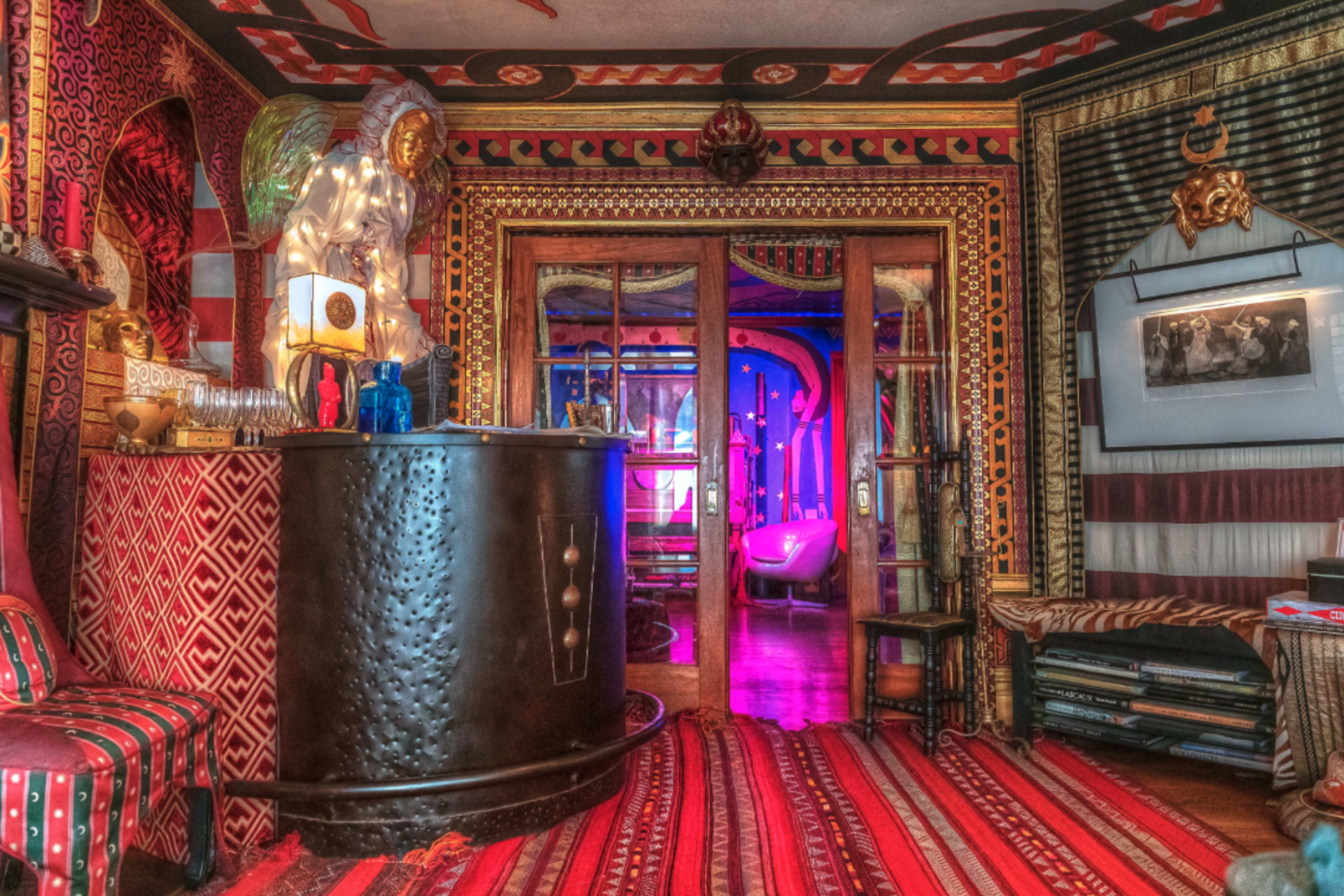 The image shows a colorful and elaborately decorated room featuring patterned walls, a bar counter, and a visible seating area.
