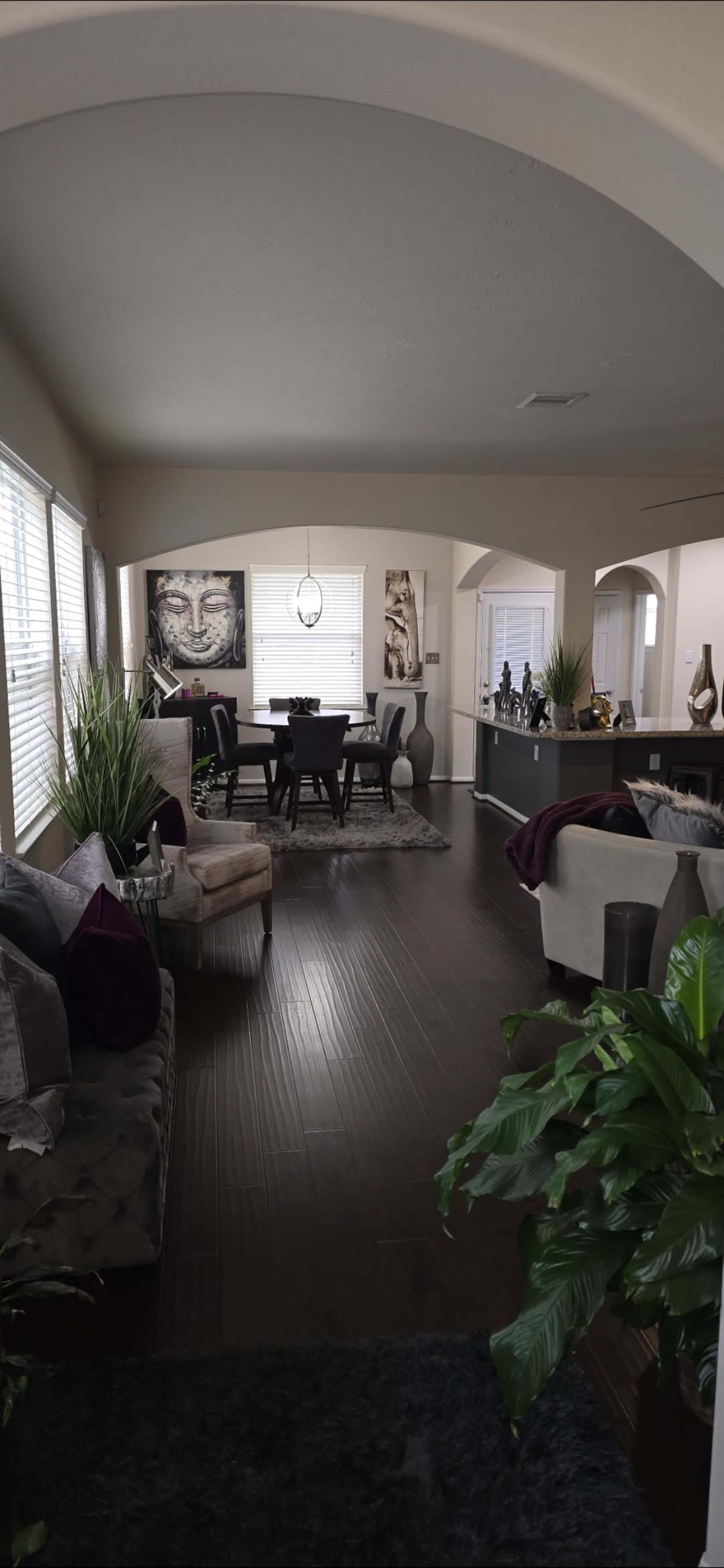 A spacious living area and dining space with modern furniture, decorative plants, and art pieces on the walls.