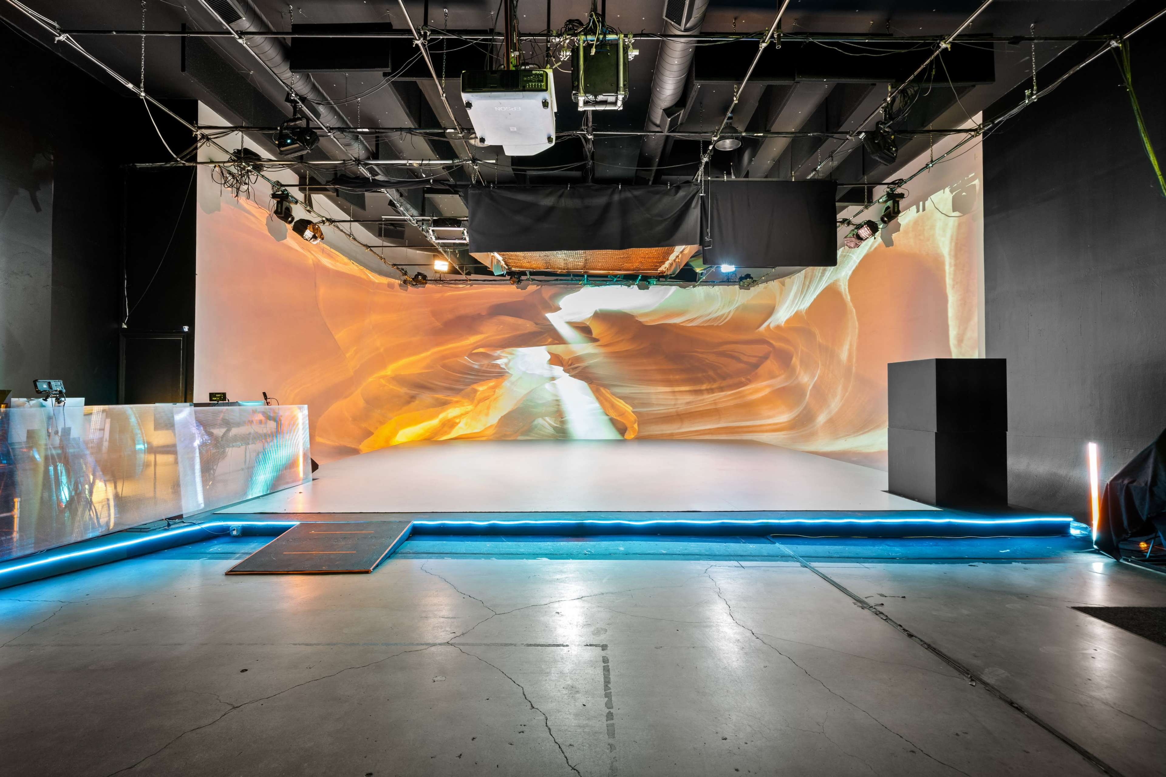 An empty performance space with a large projected backdrop and a illuminated stage area.