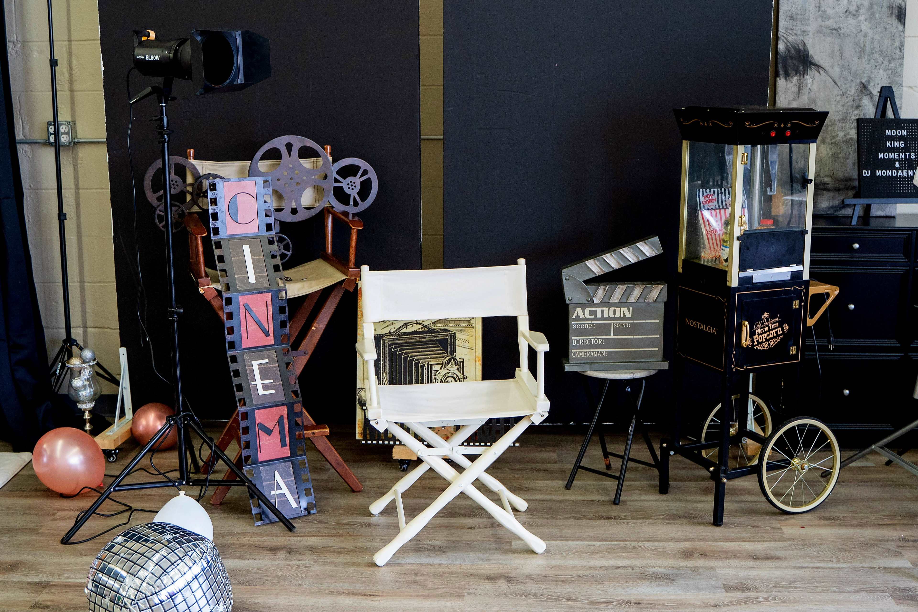A film-themed setup including a director's chair, a popcorn machine, a cinema sign, and various movie-related props.