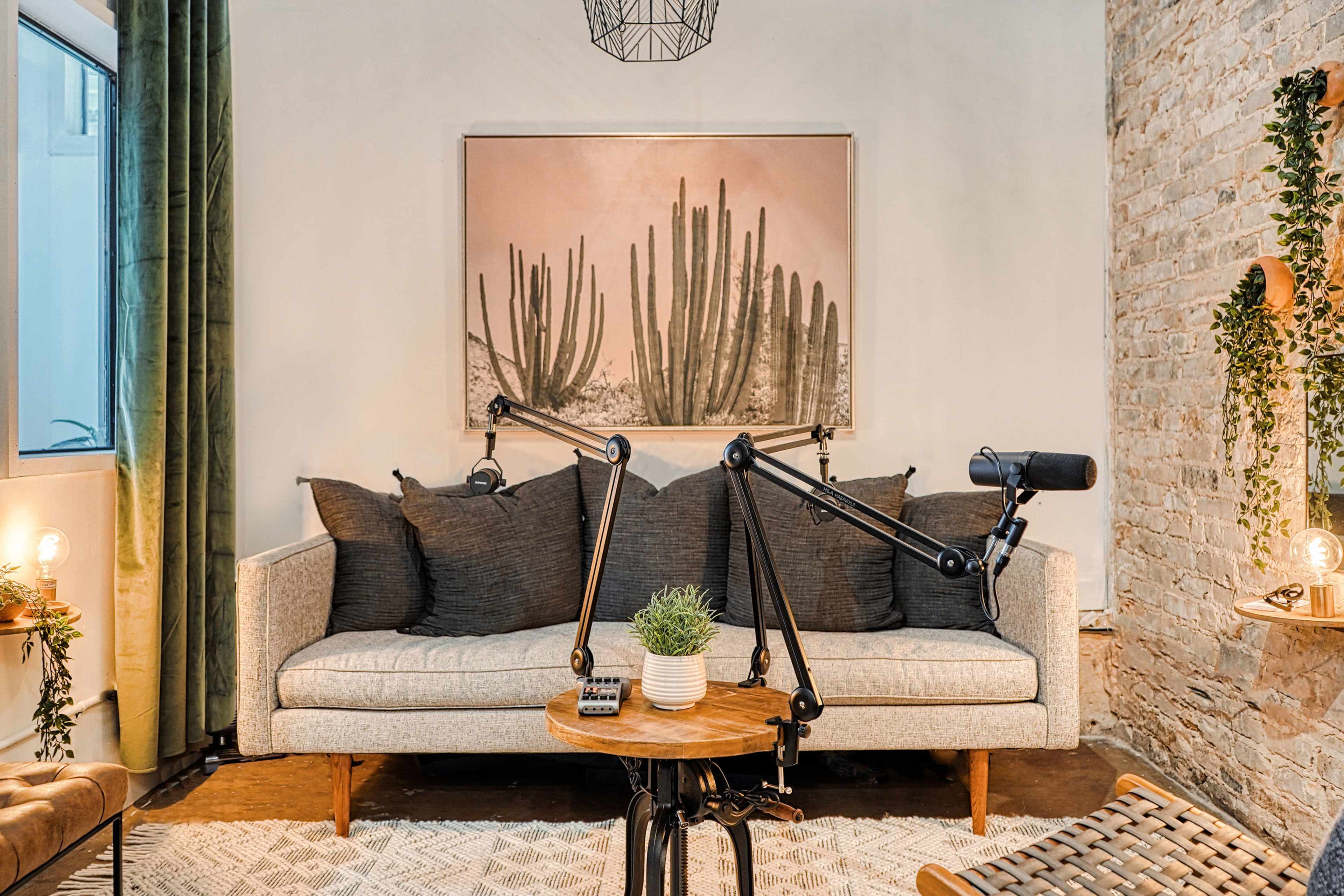 A cozy living space with a light-colored sofa, decorative plants, and a microphone setup on a wooden table.