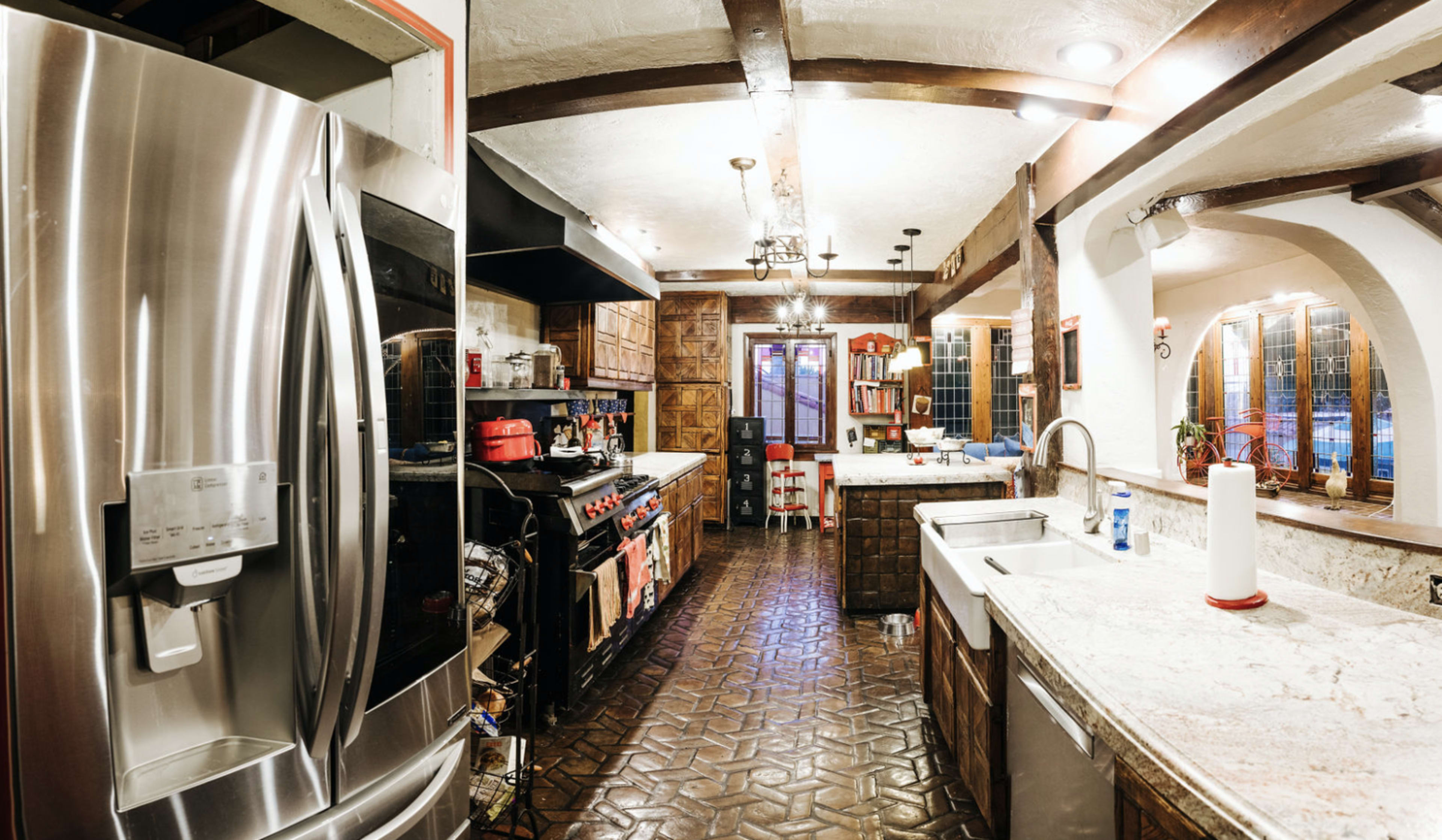 A spacious kitchen with stainless steel appliances, wooden cabinets, and a large sink, featuring a mix of modern and rustic elements.