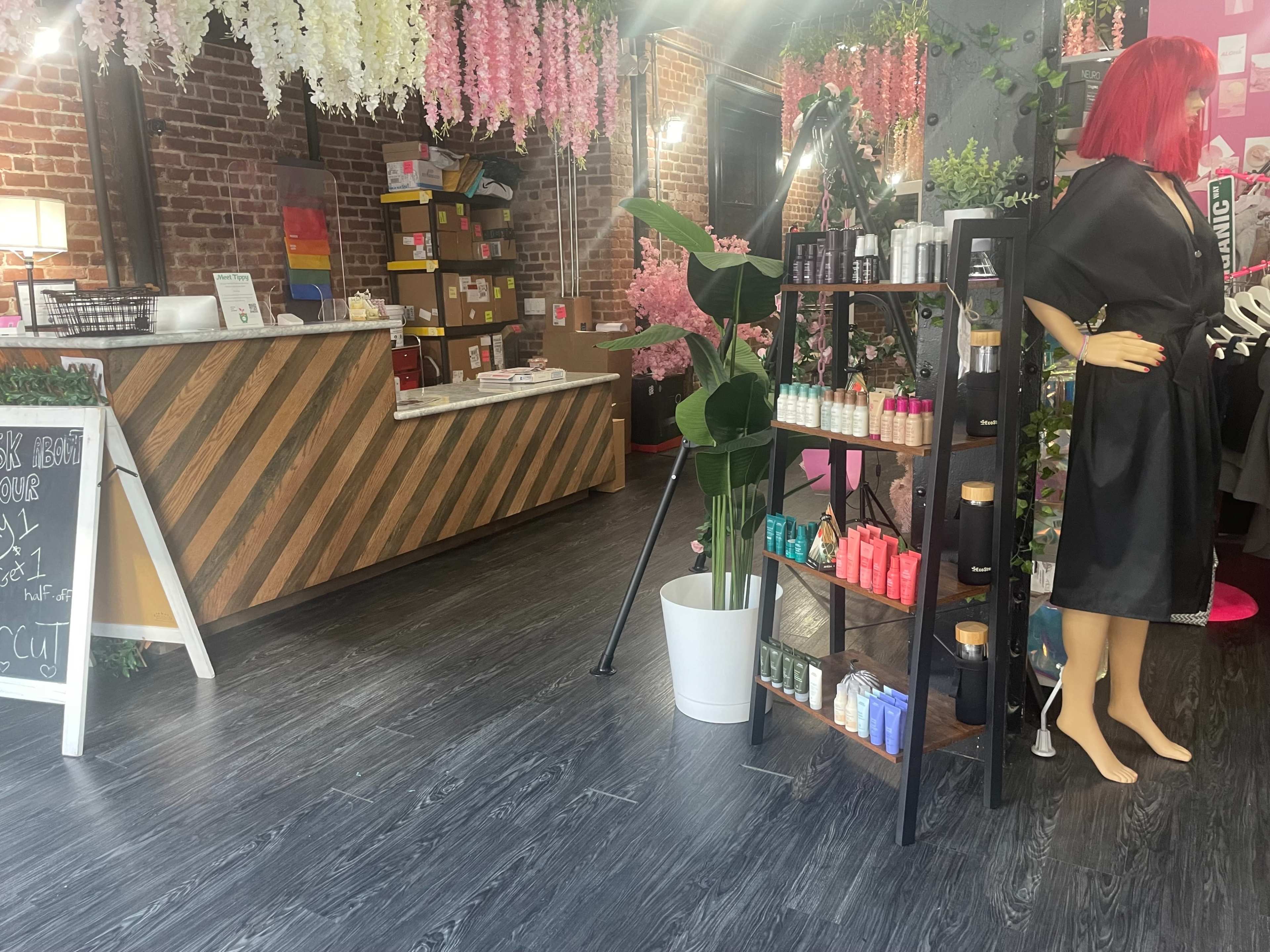 A modern beauty shop interior with a reception desk, a display of products on shelves, and a mannequin in a robe.