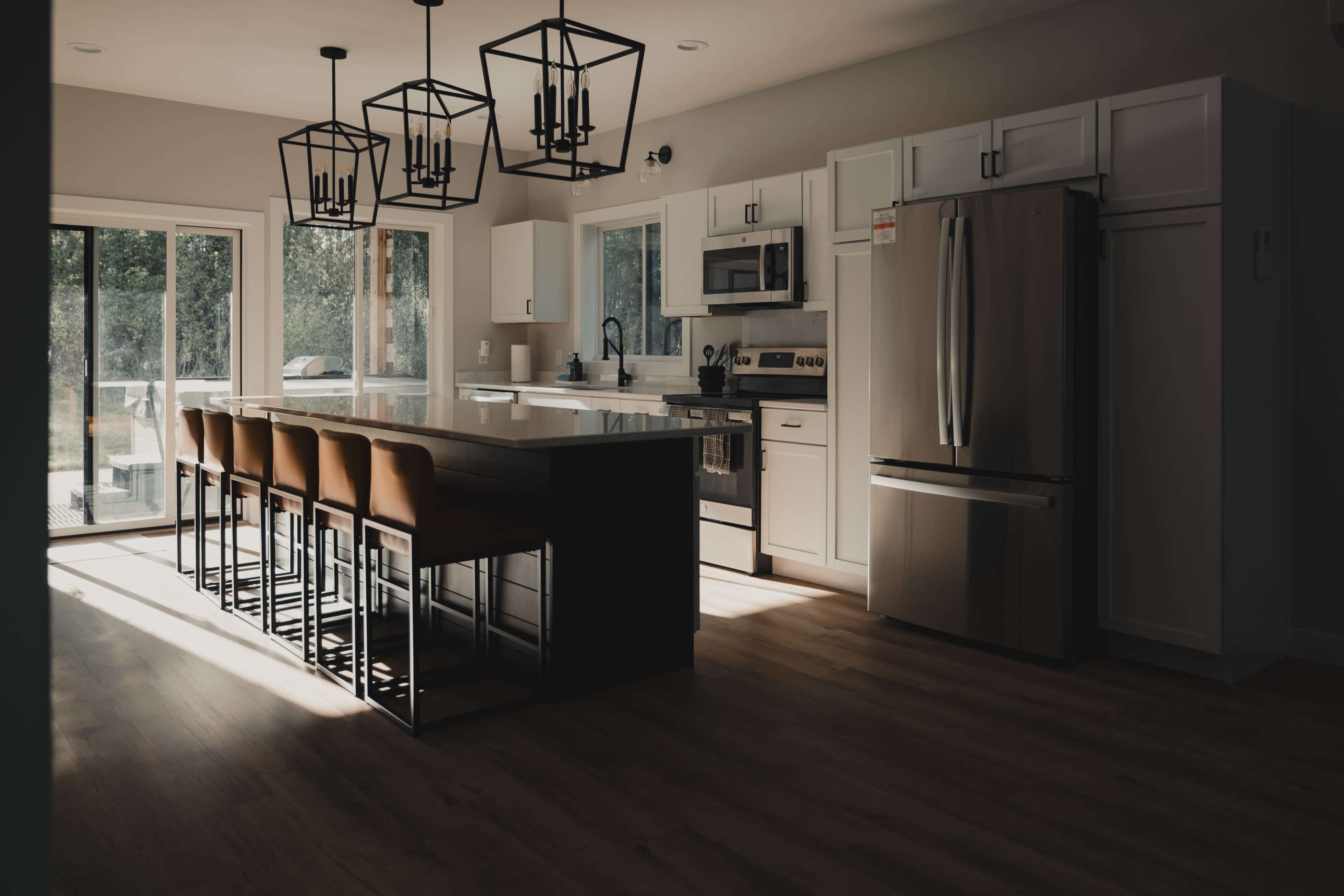 The kitchen features a large island with bar seating, modern appliances, and pendant lighting hanging above.