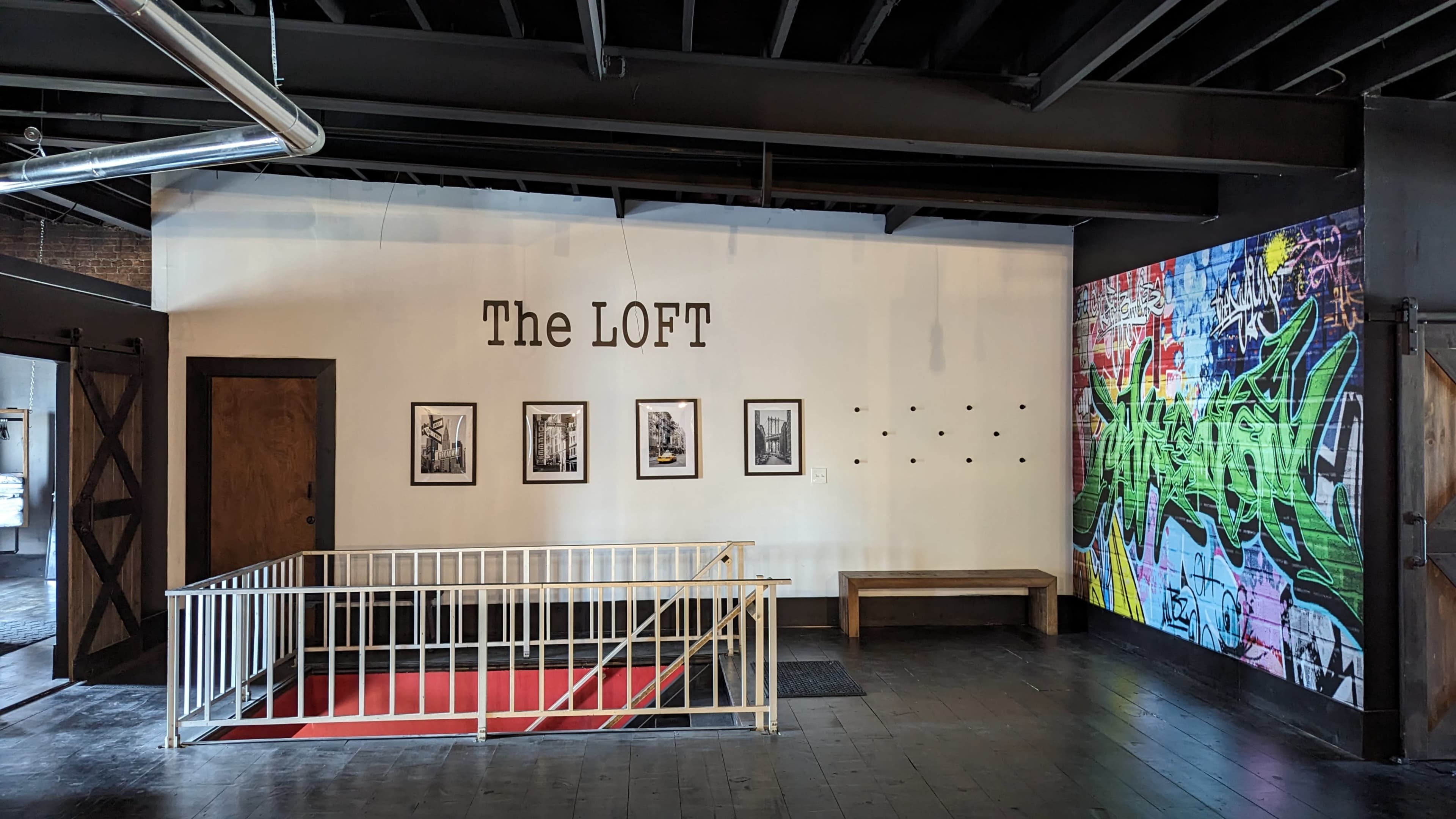 An interior space labeled "The LOFT," featuring a wall with four framed black-and-white photographs and a colorful graffiti mural on the adjacent wall.