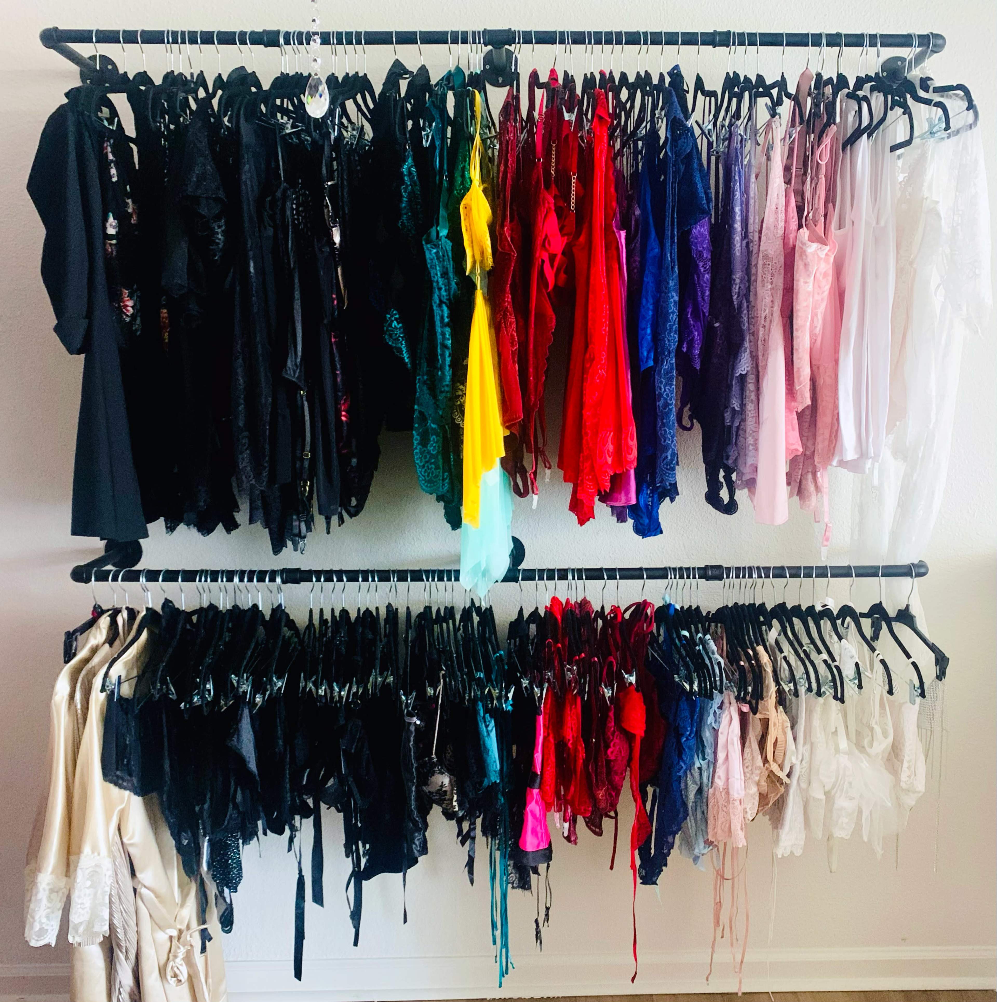 A clothing rack displays a variety of dresses and lingerie organized by color.