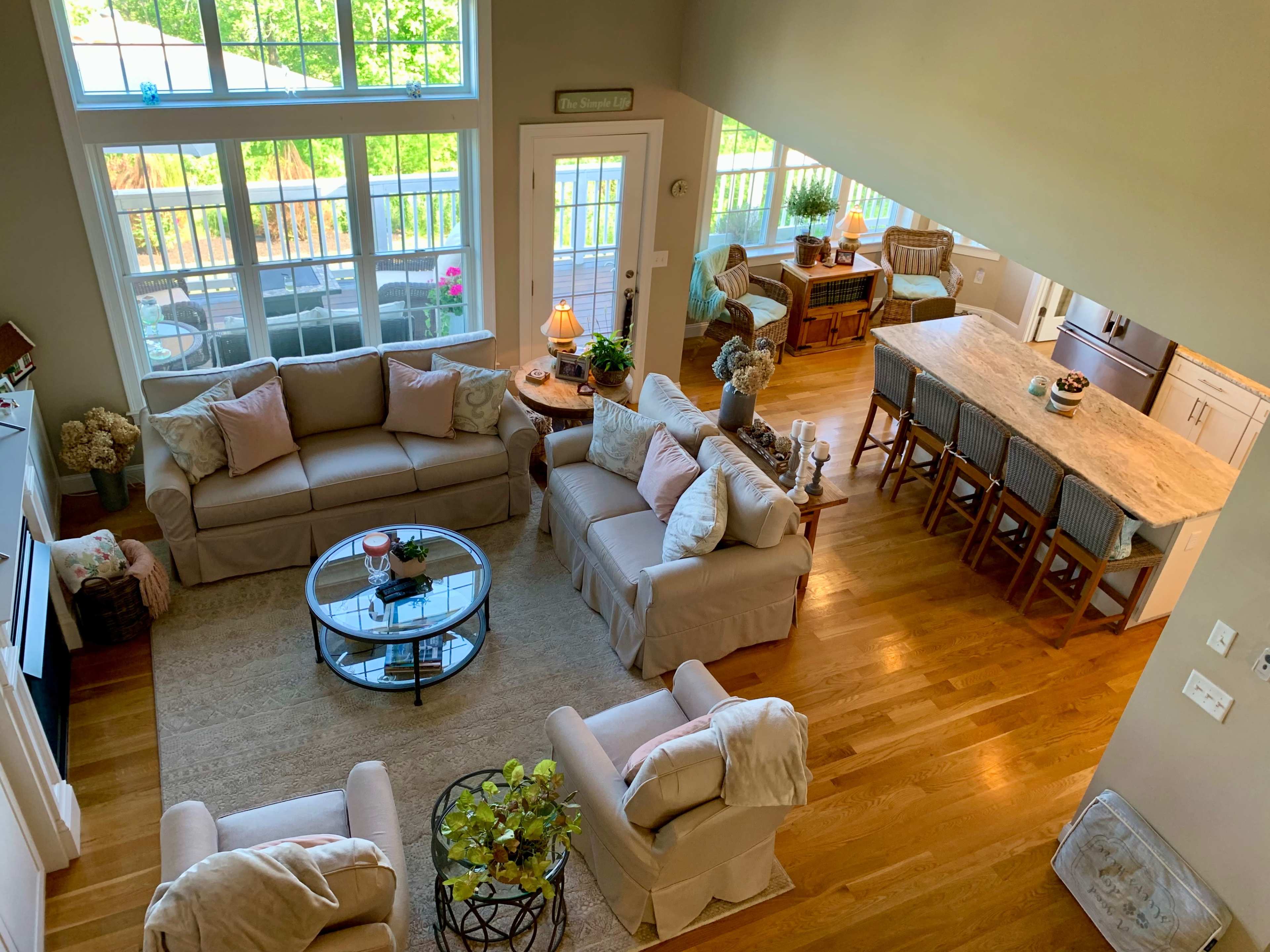 A spacious living area with light-colored furniture, a round glass coffee table, and a connected kitchen featuring a large island and bar seating.
